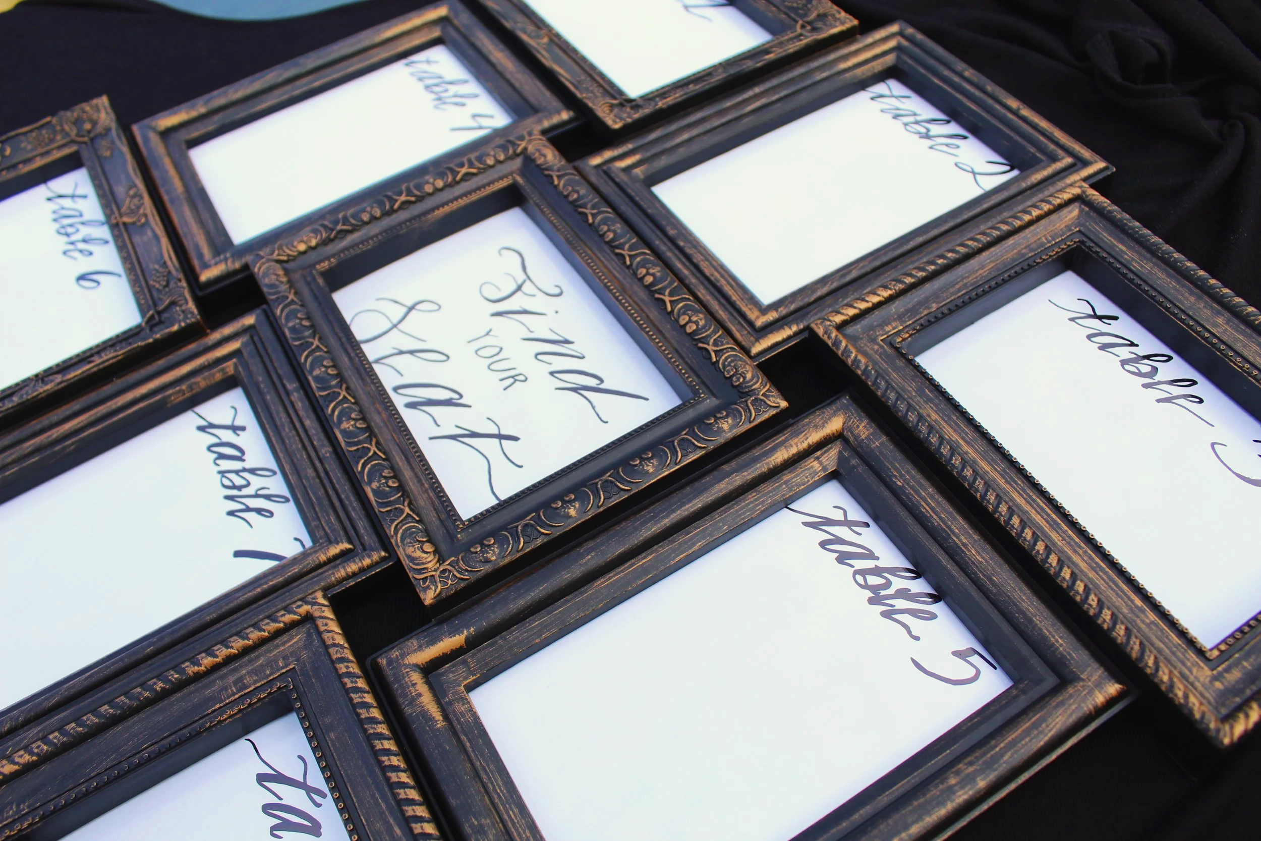 Multiple vintage-style empty picture frames with handwritten signs.
