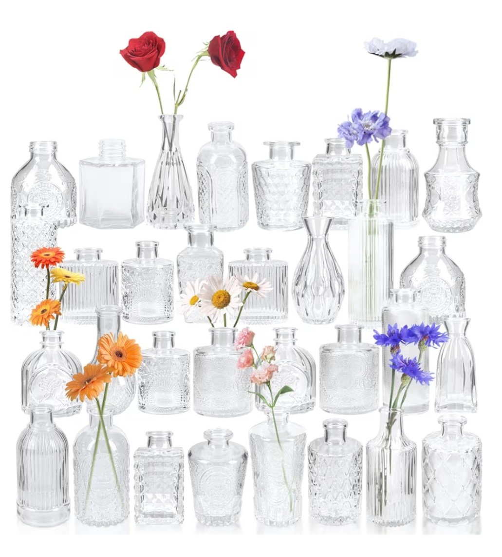 A collection of clear glass bottles and vases with colorful flowers.