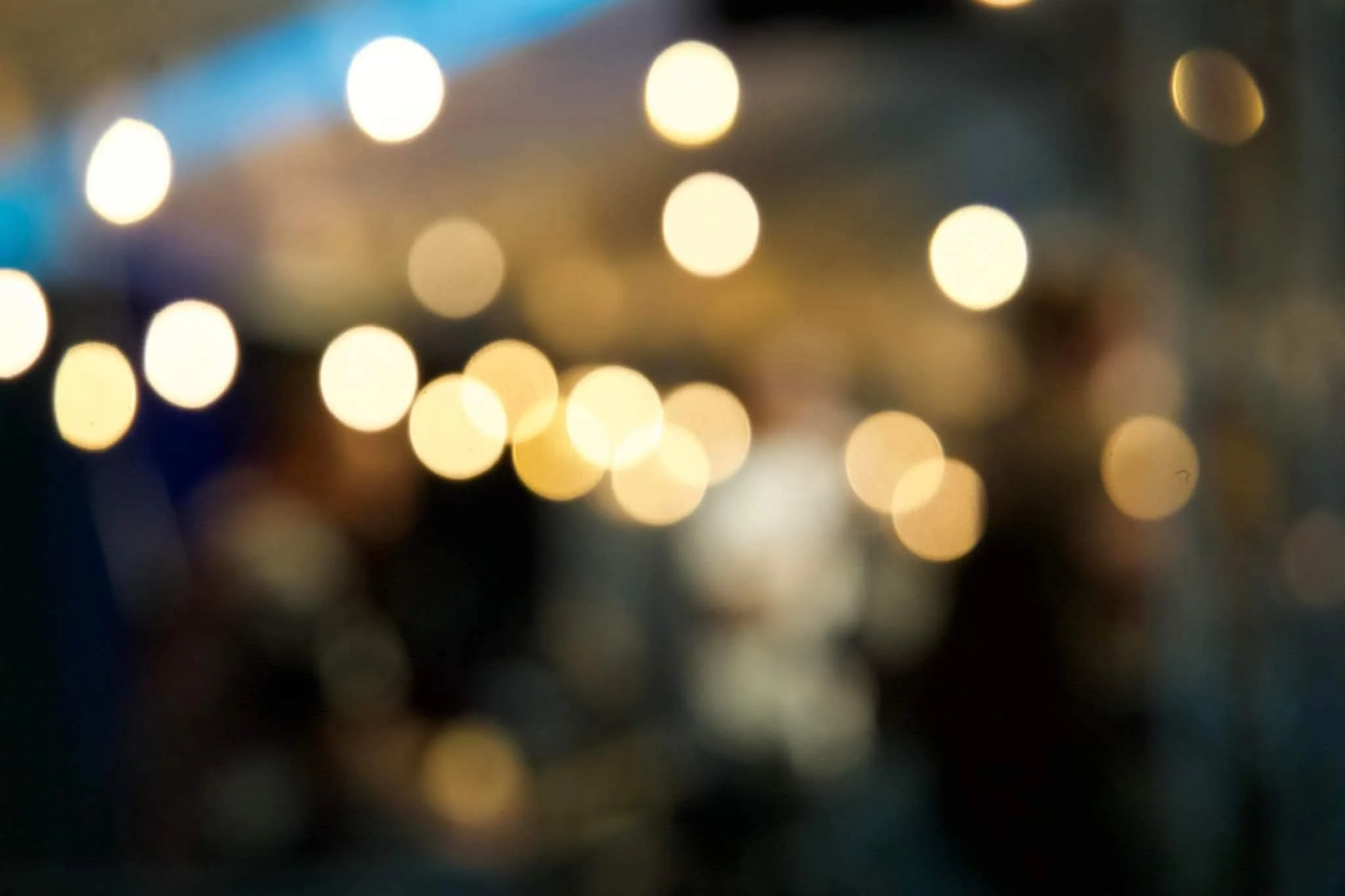 Blurred image with circular bokeh lights in warm tones, likely at night or in a dimly lit environment.
