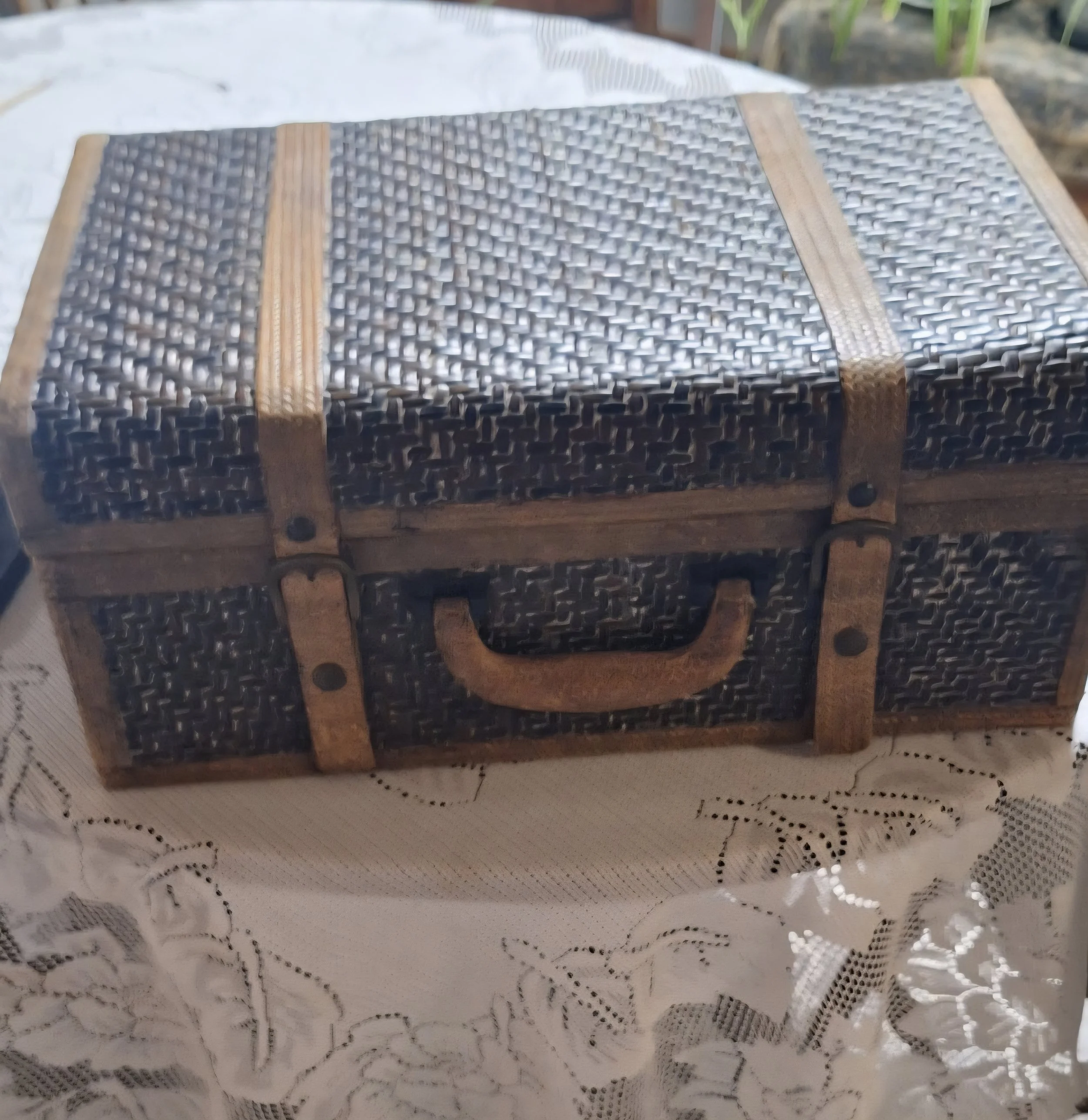 A vintage suitcase with leather straps and a handle, placed on a lace tablecloth.  Included in wedding decoration rental package.