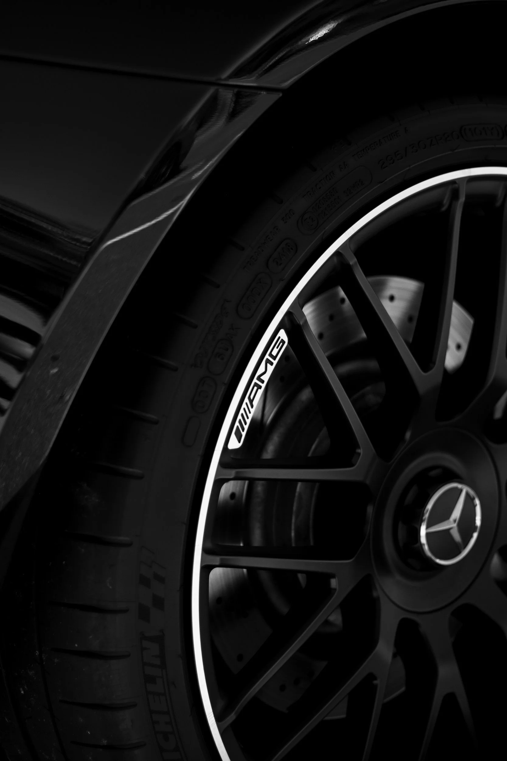 Close-up of a black Mercedes-Benz vehicle wheel with a Pirelli tire and AMG branding, featuring a metallic Mercedes emblem at the center.