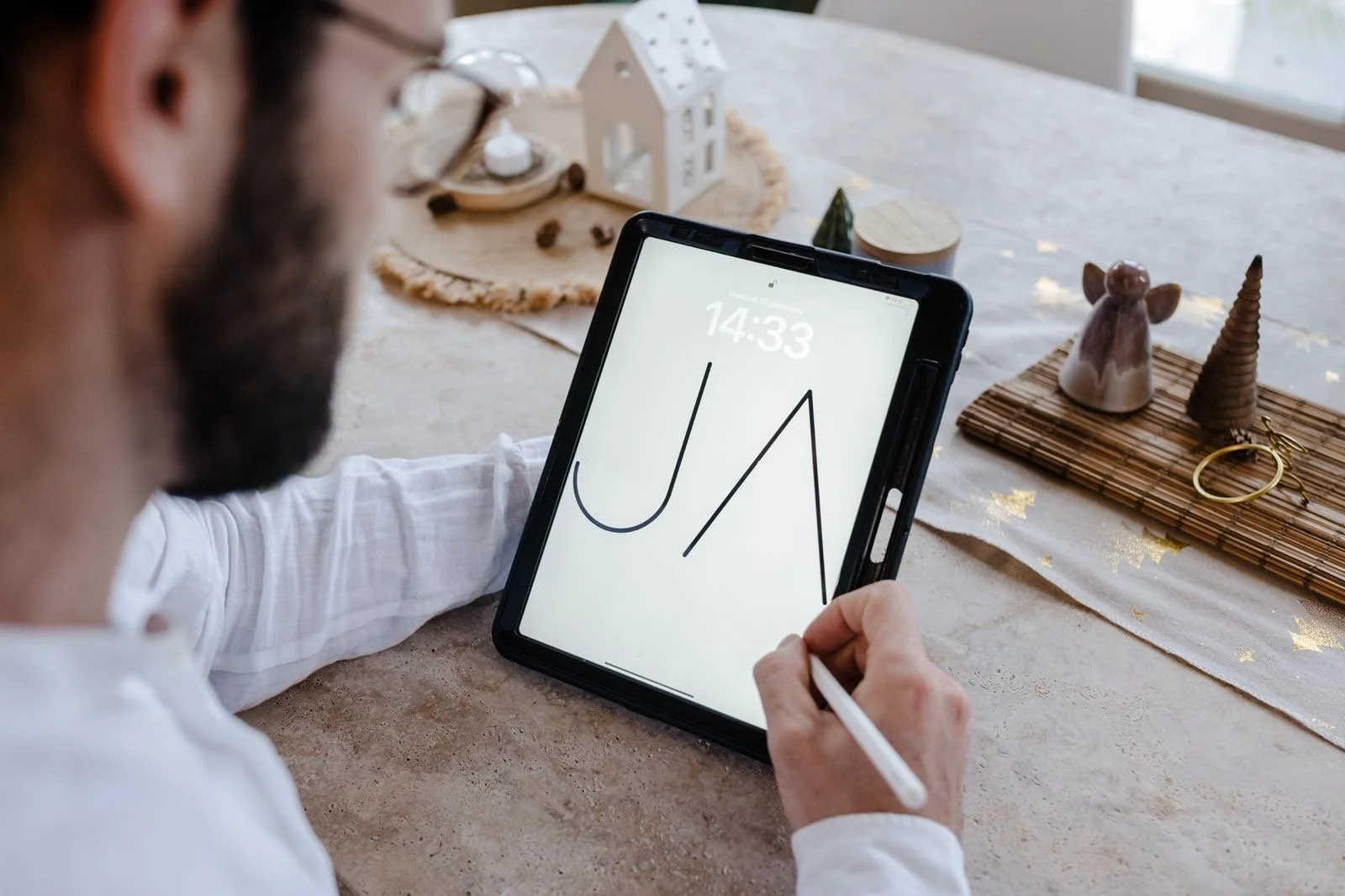 Un homme dessine sur une tablette avec stylet, la tablette affiche les lettres "J" et "A".