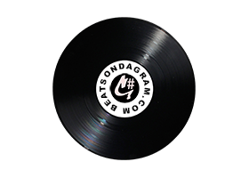 Close-up of a black vinyl record with a white label in the center, featuring text and a logo.