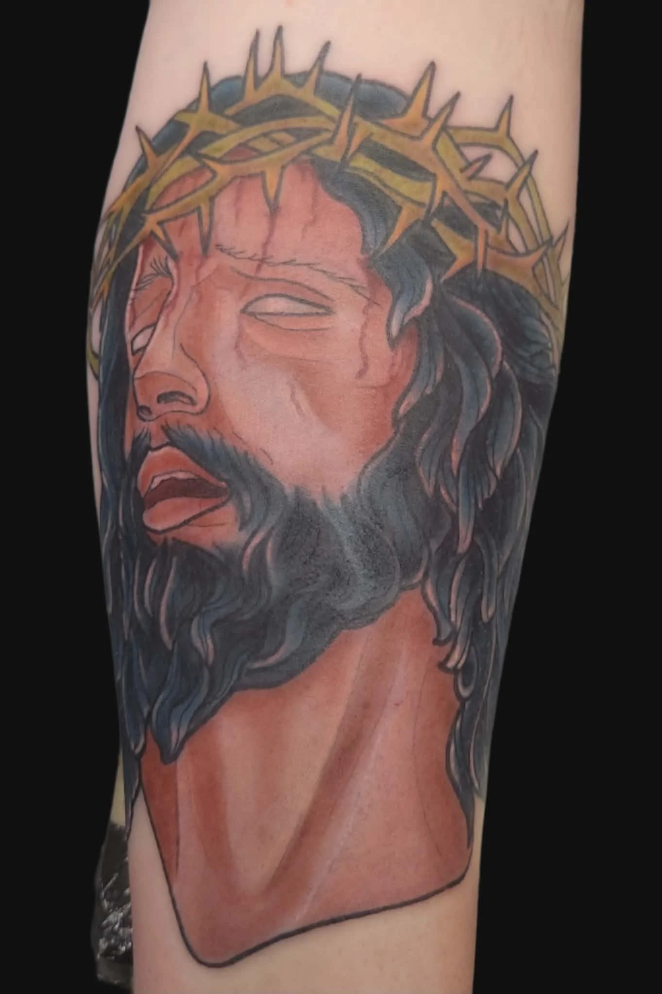 Tattoo of Jesus Christ wearing crown of thorns on arm.