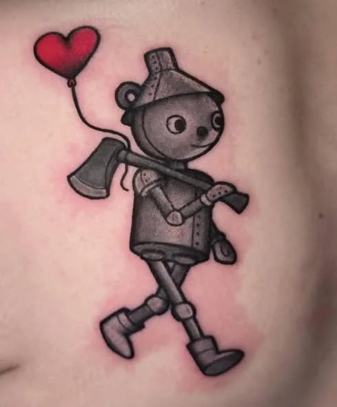Tattoo of a cartoon robot bear holding an axe and a balloon shaped like a heart.