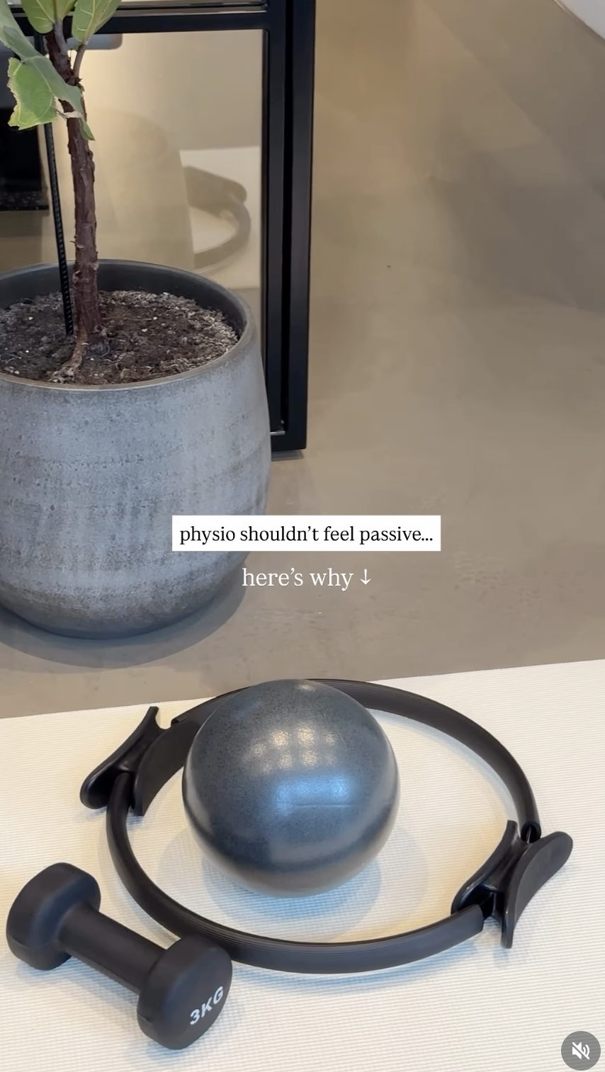 A fitness setup featuring a black kettlebell, a circle resistance band, and a small black dumbbell with 3 kg weight, placed on a white mat, with a potted plant and furniture in the background.
