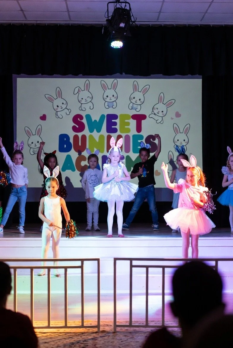 Children dressed as bunnies performing on stage during a children's show titled 'Sweet Bunnies.'