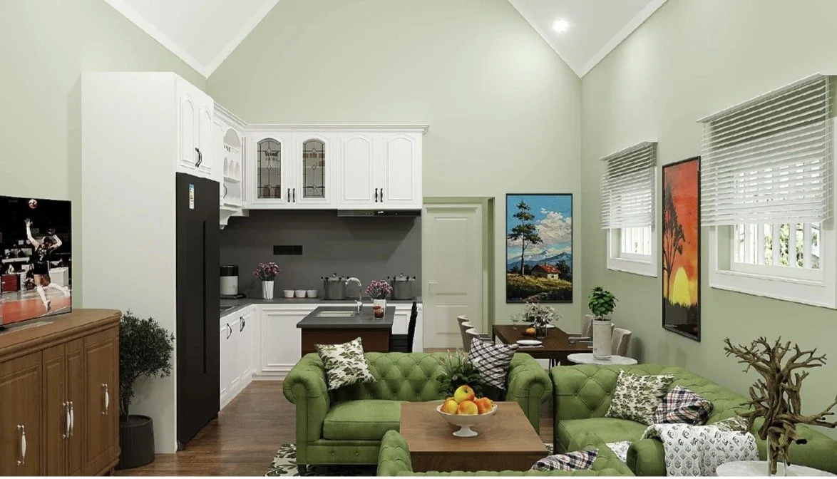 Living room and kitchen area with green sofas, wooden dining table, and white kitchen cabinets, decorated with wall art and plants.