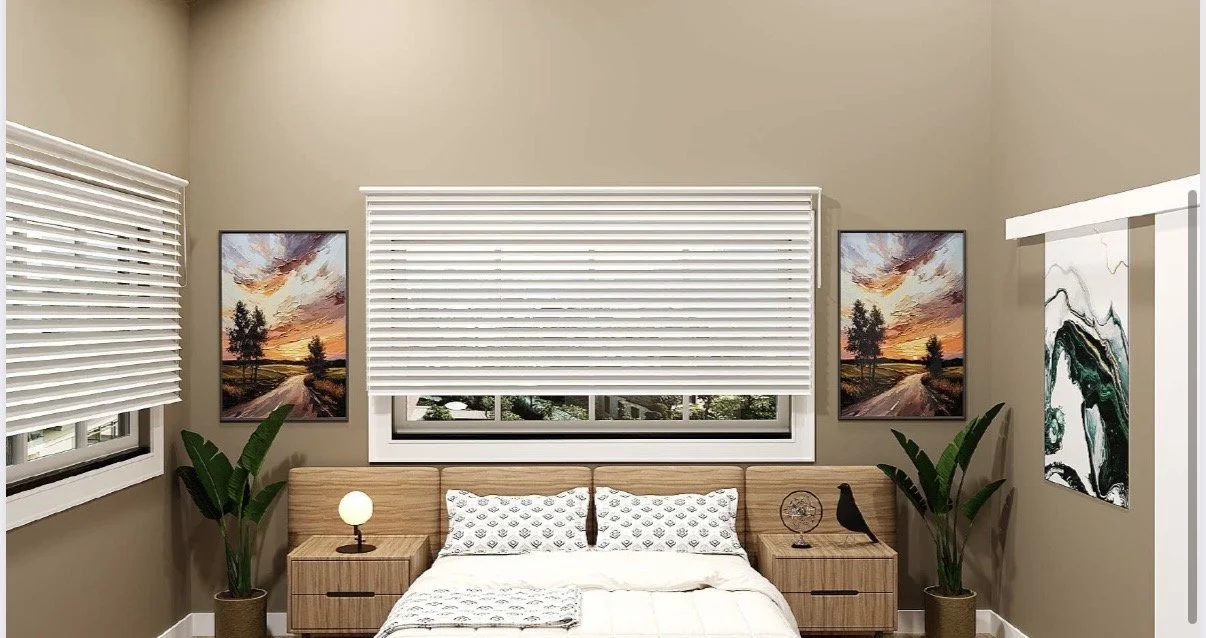 A bedroom with beige walls, two windows with white blinds, a wooden bed with white and patterned pillows, two matching wooden nightstands, a small round lamp on the left nightstand, a decorative item and a bird figurine on the right nightstand, and framed landscape and abstract art on the walls.