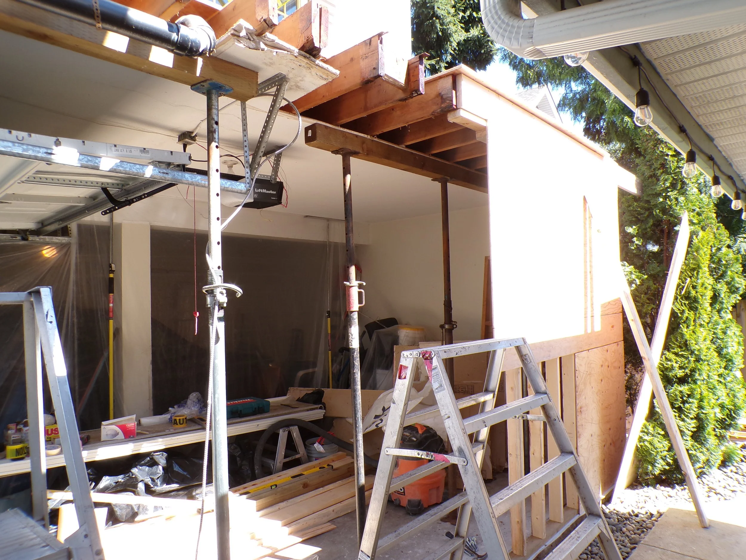 Construction work on a house extension with scaffolding, ladders, and building materials visible outside a house.
