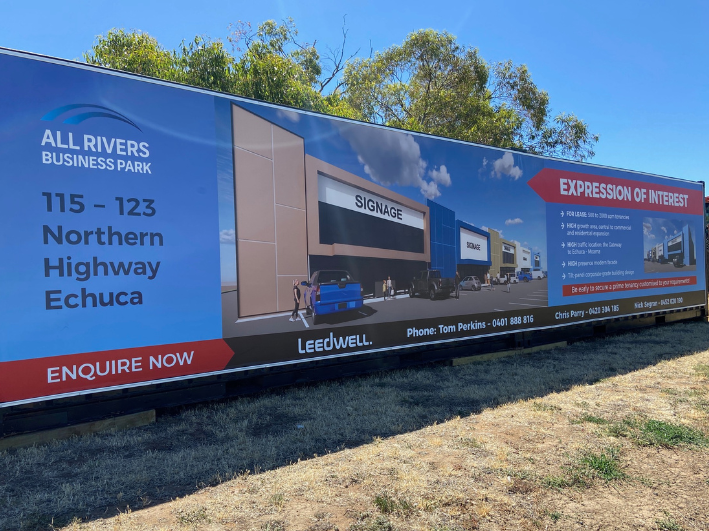 Large billboard advertisement for All Rivers Business Park located at 115-123 Northern Highway Echuca. The billboard shows a digital rendering of a commercial building and parking lot, with cars and people. The ad promotes the business park with details and contact information, and emphasizes the expression of interest for leasing opportunities.