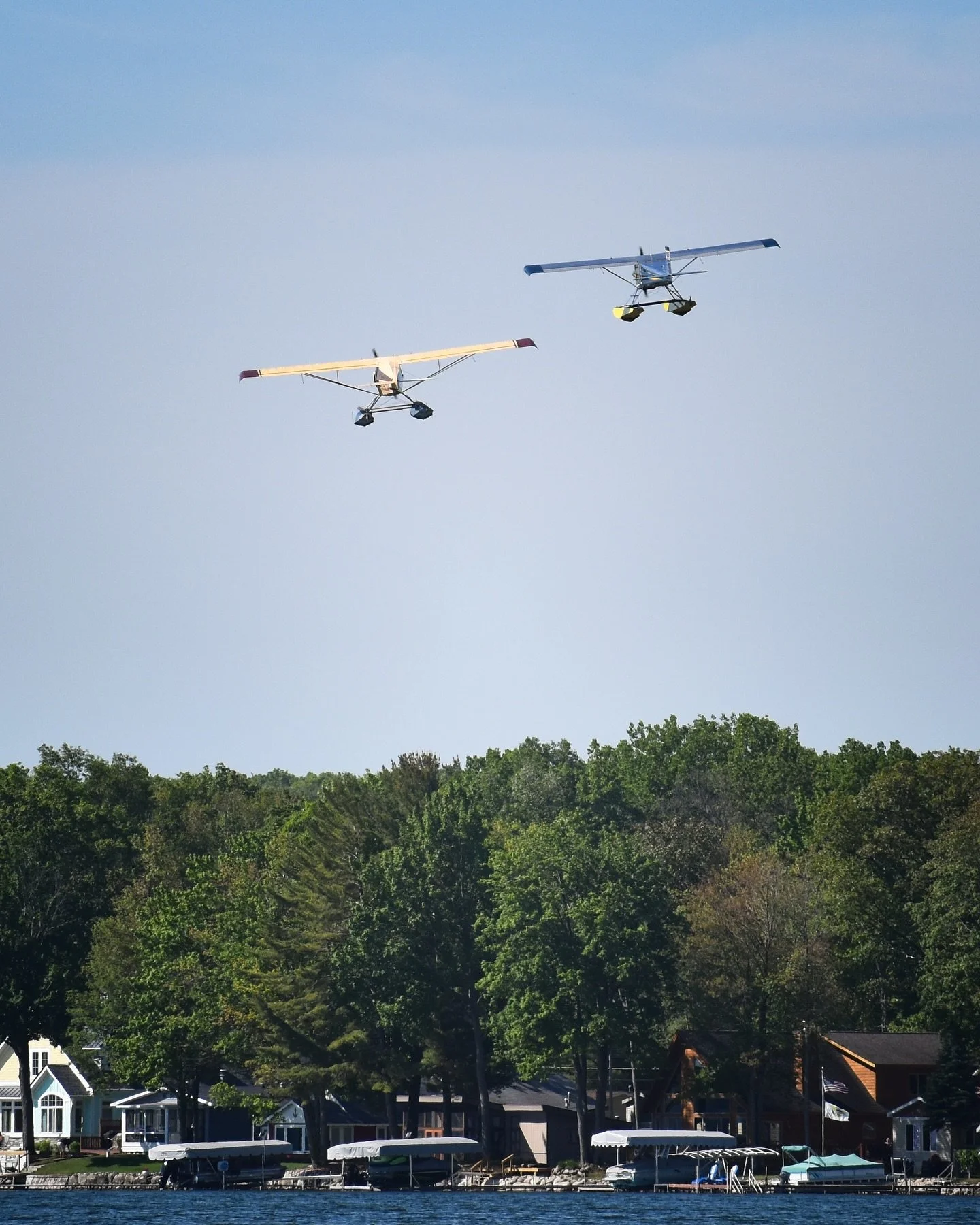 Formation flight of two seaplanes over a lakeside community in Michigan