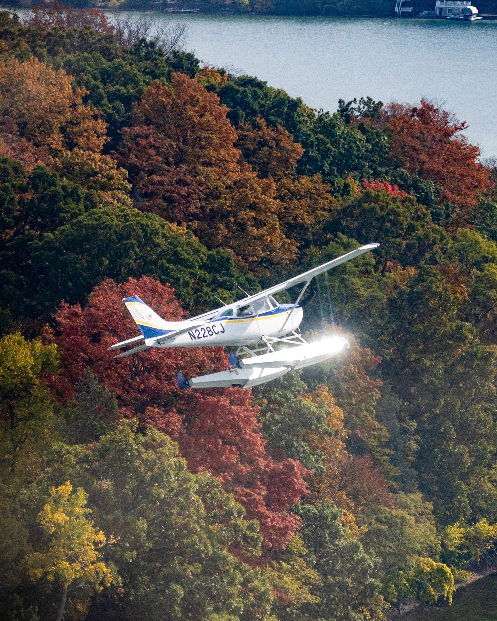 Seaplane flying over a Michigan lake with fall colors