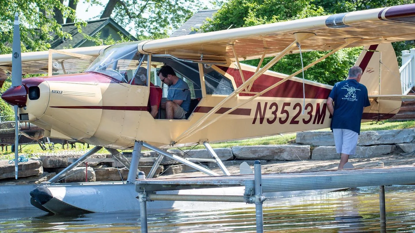 Seaplane on floats docked at a lake with pilots preparing for flight