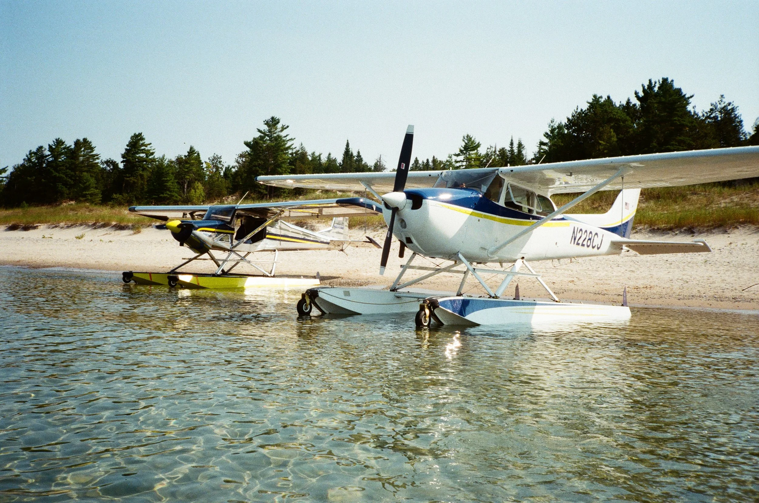Seaplanes parked on the water along a sandy Michigan shoreline