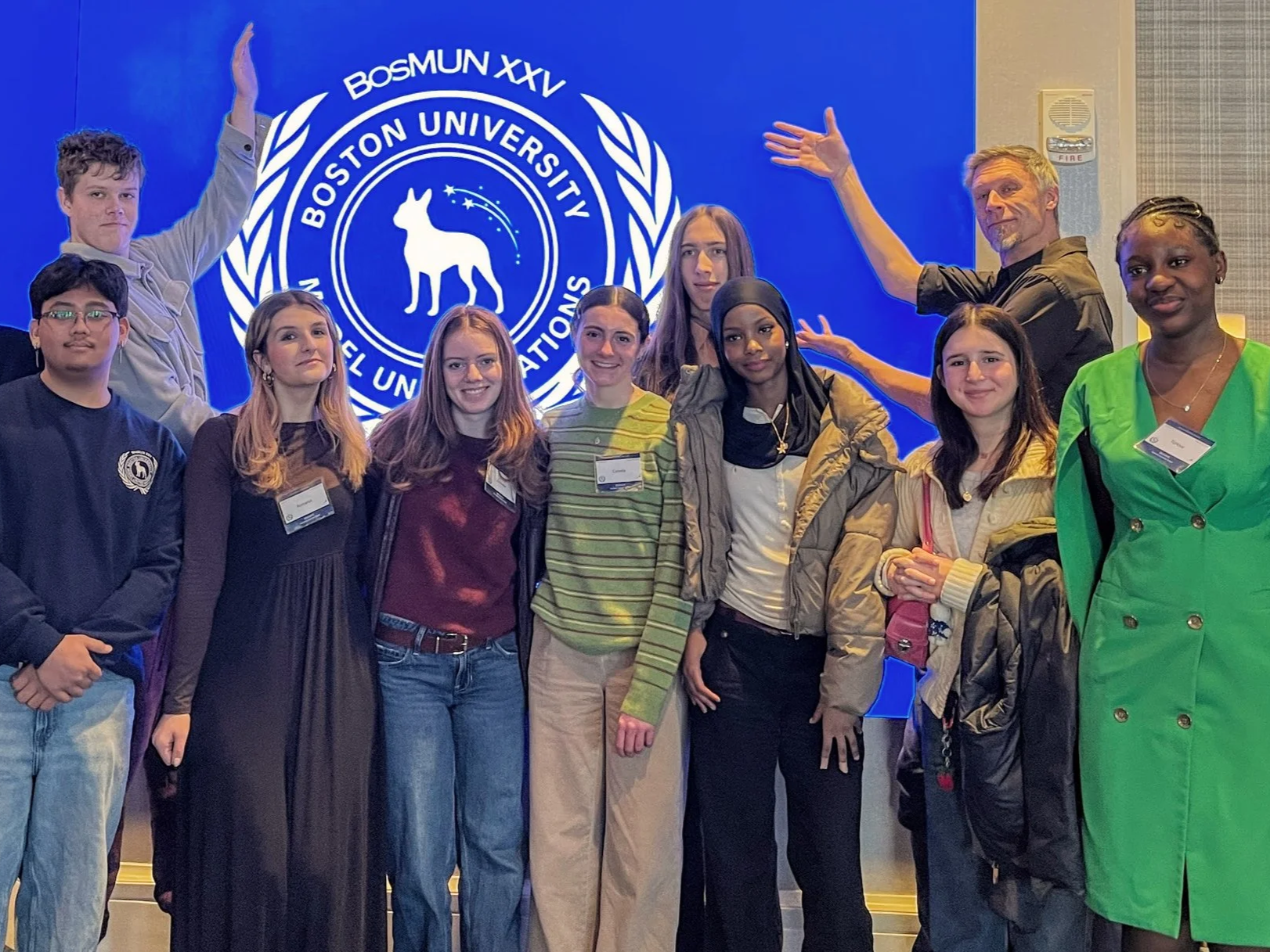 Group of people, mostly young, standing in front of a blue backdrop with the Boston University emblem. They are smiling and looking at the camera during an event or conference.