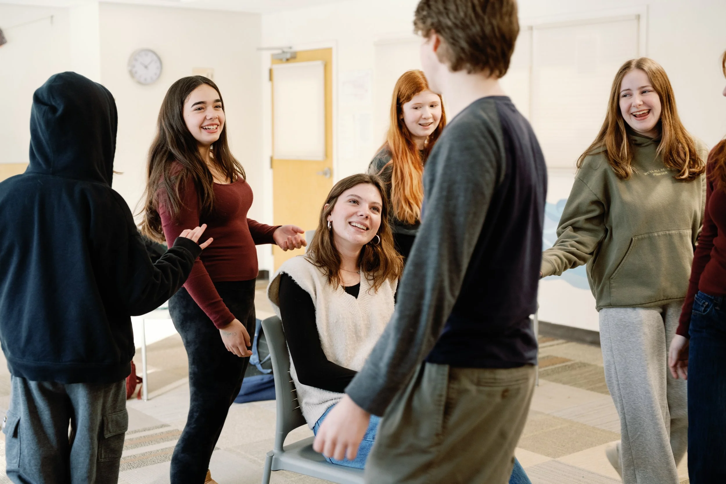 Group of young people chatting and laughing in a classroom.