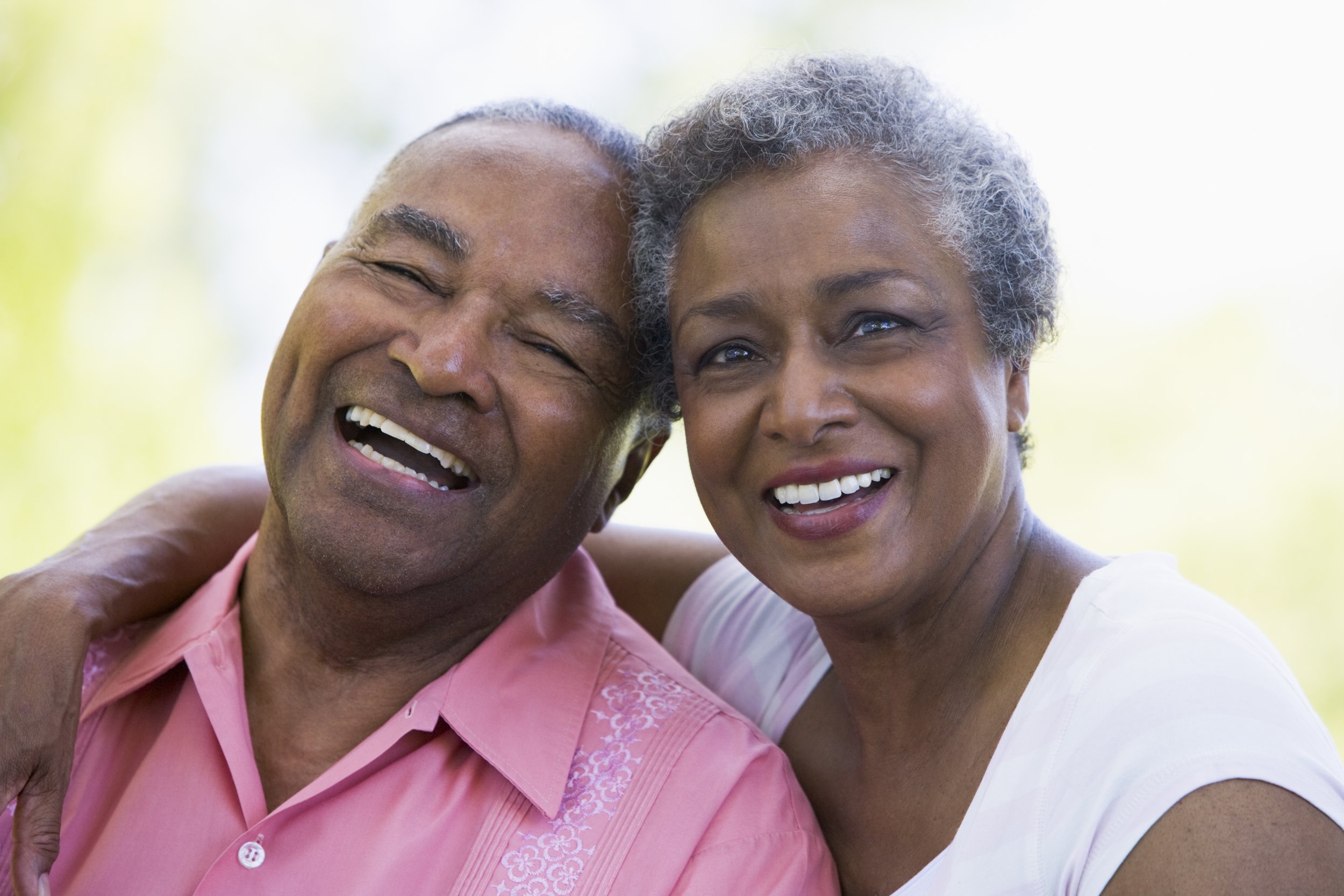 A happy middle-aged couple smiling and embracing outdoors.