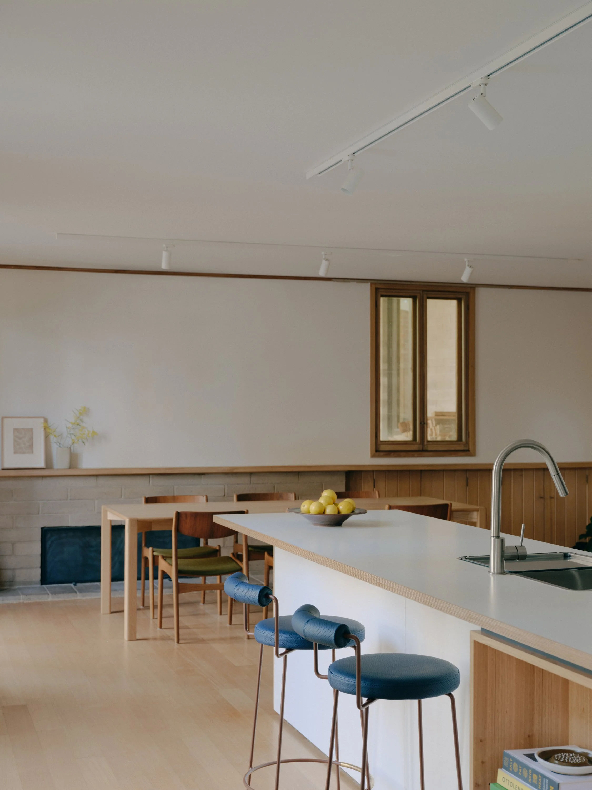 A white kitchen bench with navy barstools 
