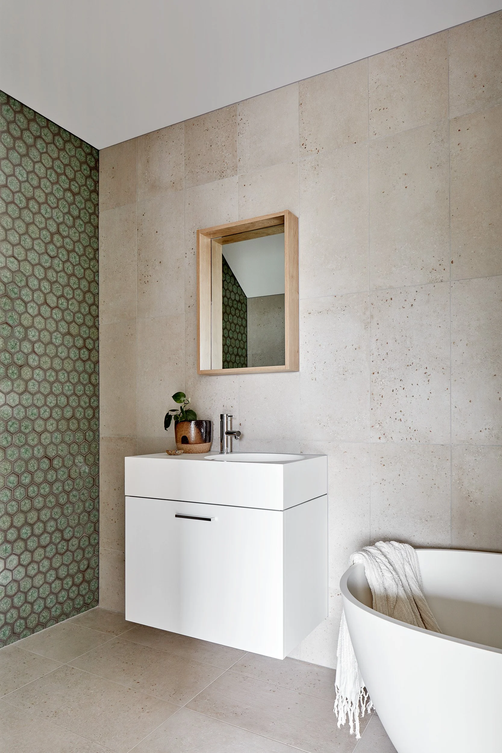 Tiled bathroom with white vanity and a small bathtub