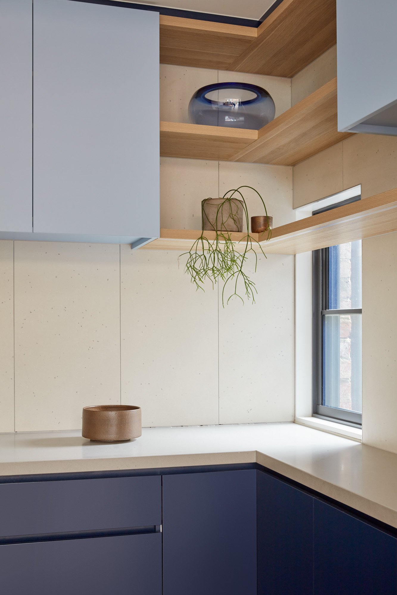 Two tones blue laminate kitchen with stone bench and timber shelves