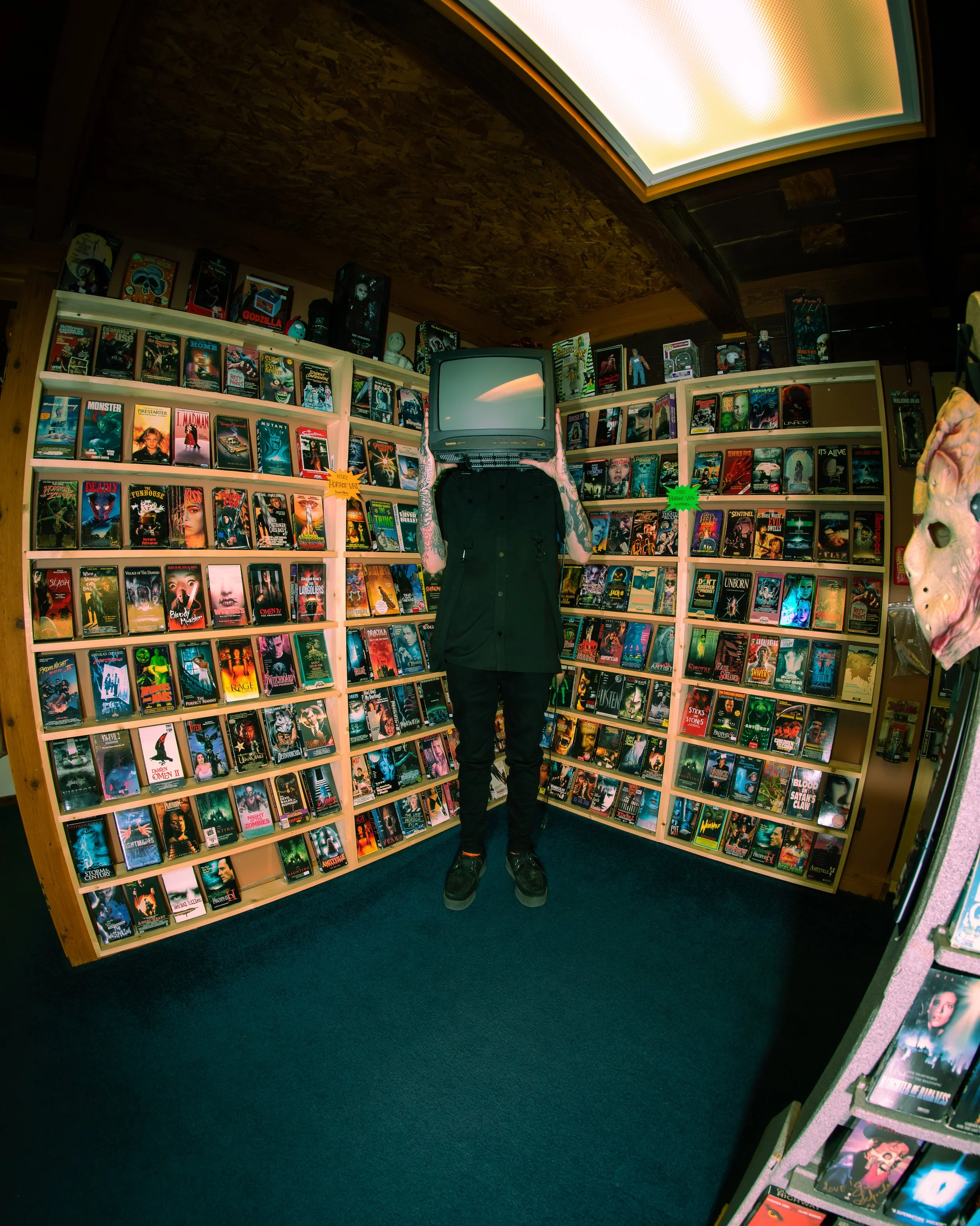 A woman with curly hair, wearing glasses and earrings, smiling in an indoor setting.
