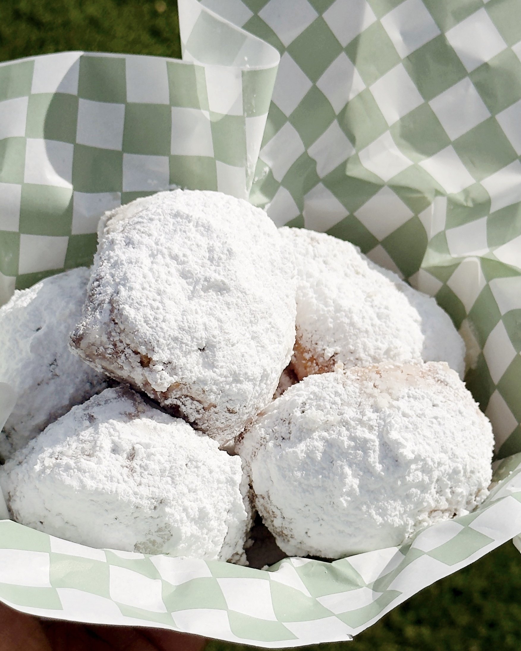 Close-up of a paper basket containing powdered sugar-coated cookies.