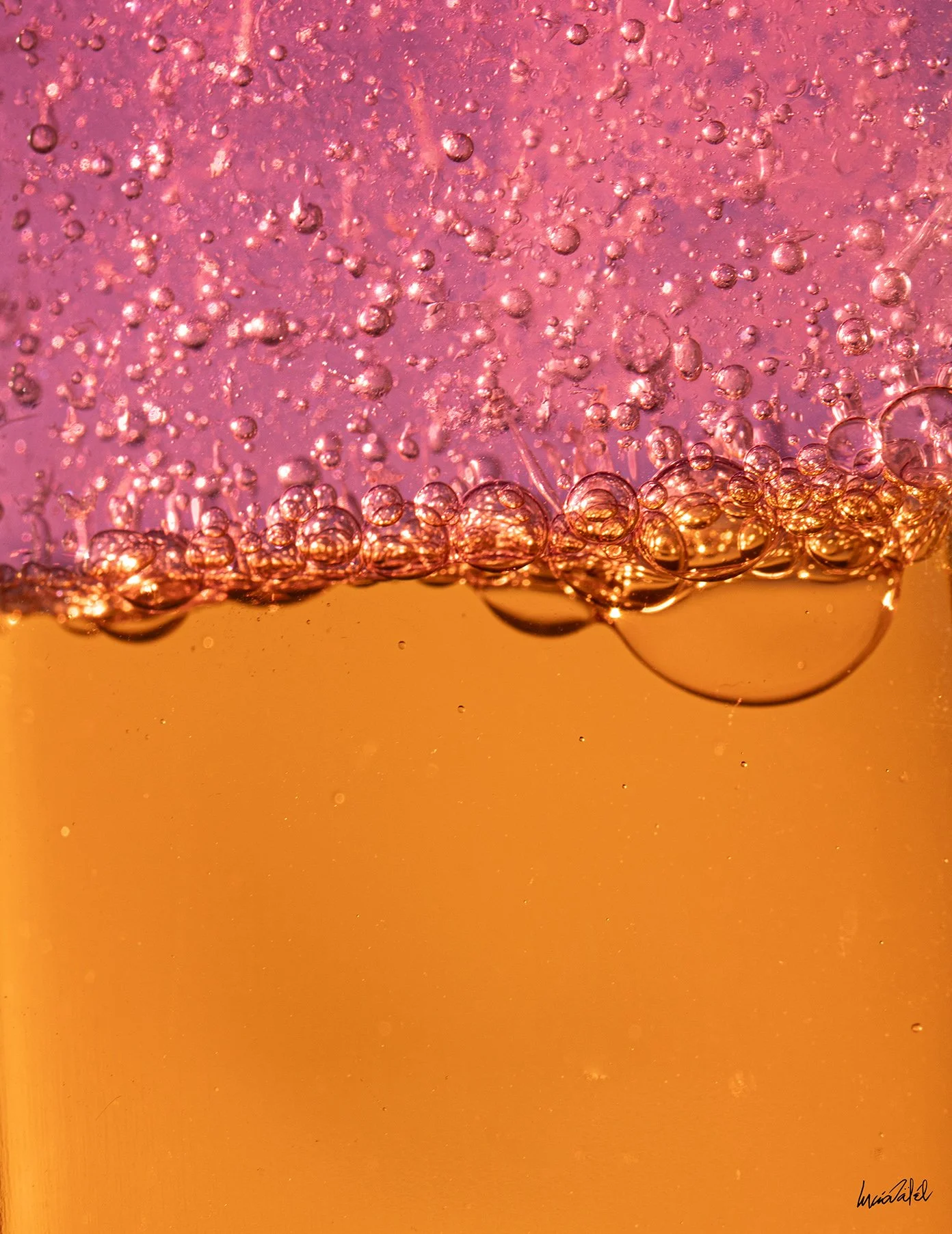 Vista macro de burbujas en líquido anaranjado y rosado.