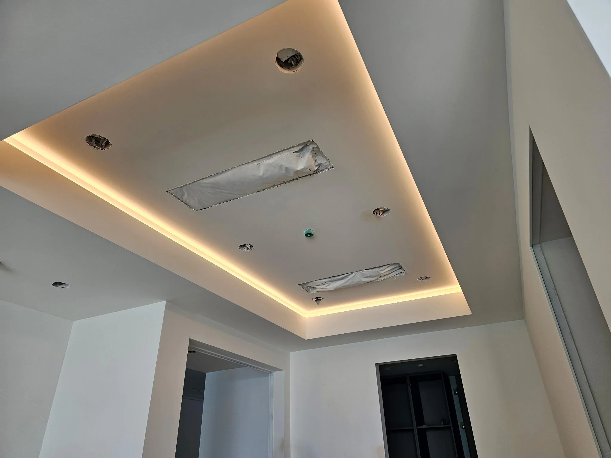 Ceiling with recessed lighting and air vents, part of a modern interior space under construction or renovation.