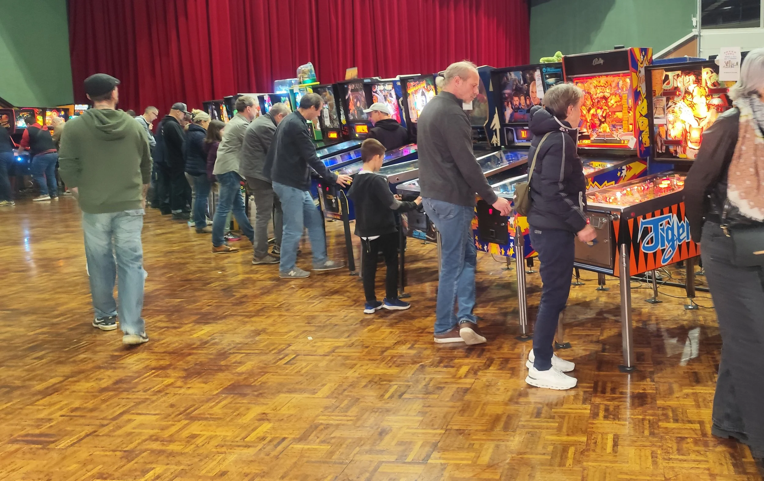 Gens jouant aux machines à sous de type flipper dans une salle d'exposition de flipper et jeux d'arcade (le salon du flipper d'Ambérieu-en-Bugey)