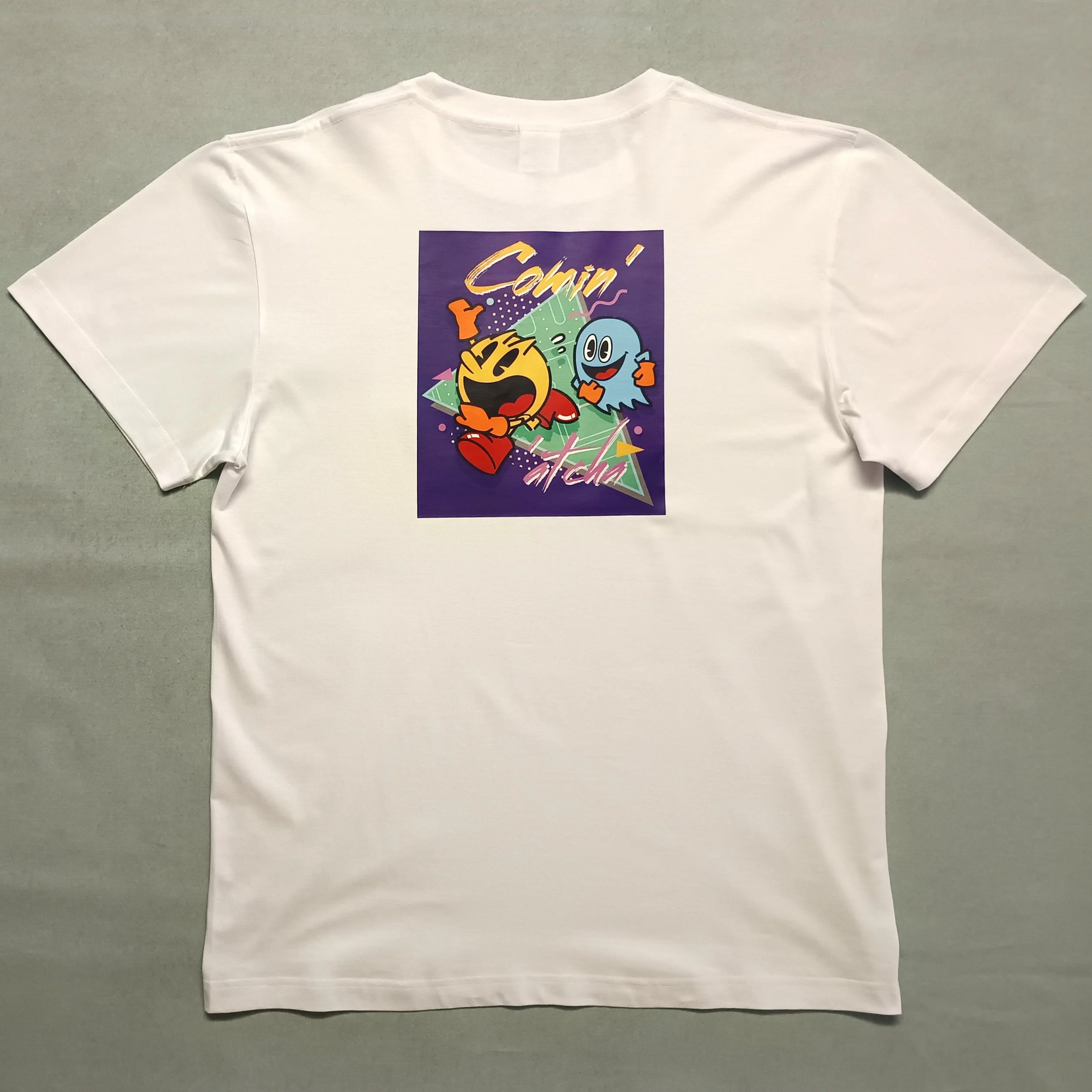 T-shirt noir style arcade rétro “COMIN’ AT CHA” inspiré de l’univers Pac-Man, avec graphisme pop années 80, ambiance pixel et esprit salle d’arcade vintage.