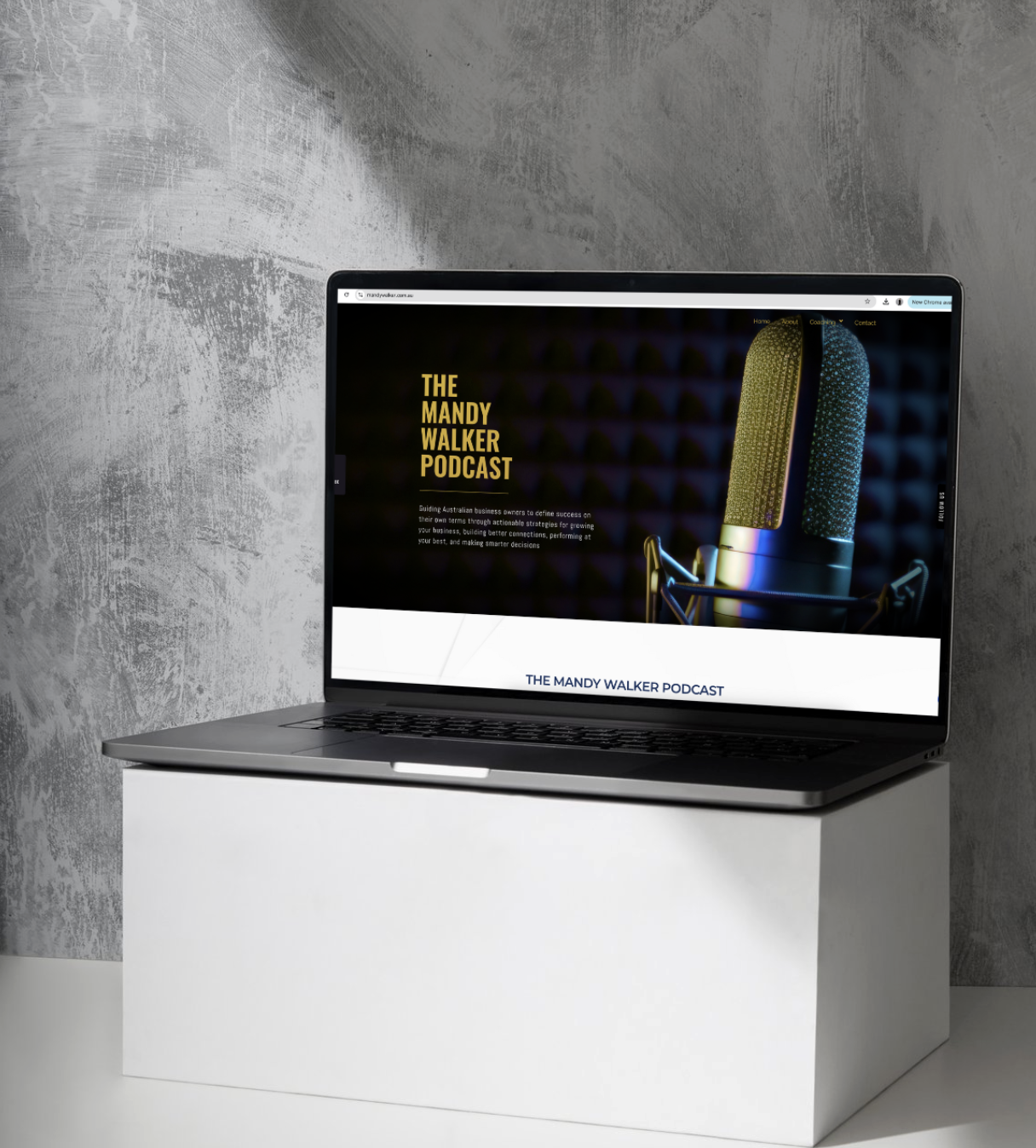 Laptop on a white stand displaying a website titled 'The Mandy Walker Podcast' with a large microphone image and dark background.