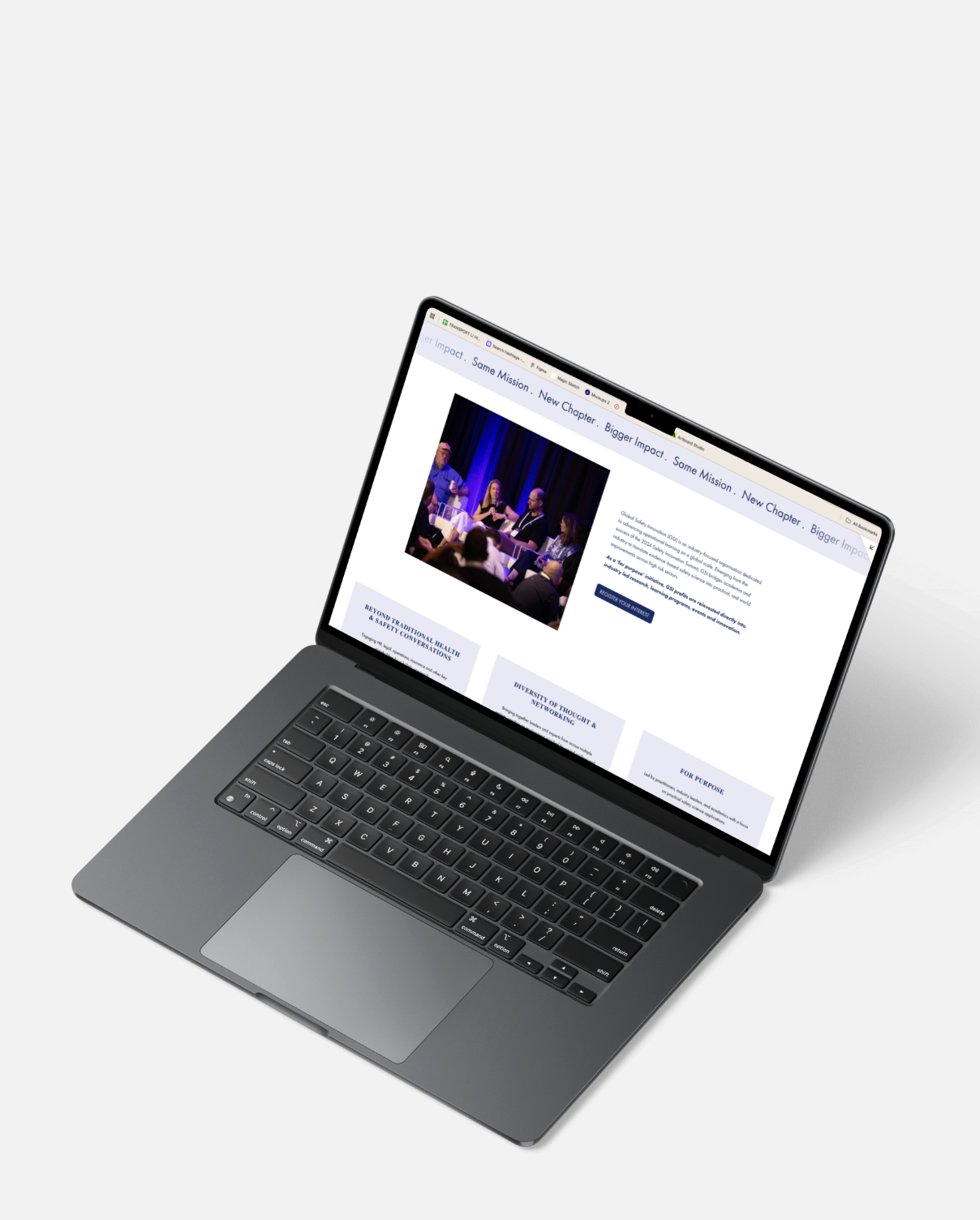 Open laptop displaying a webpage with a picture of a panel discussion on a stage with blue curtains and an audience.