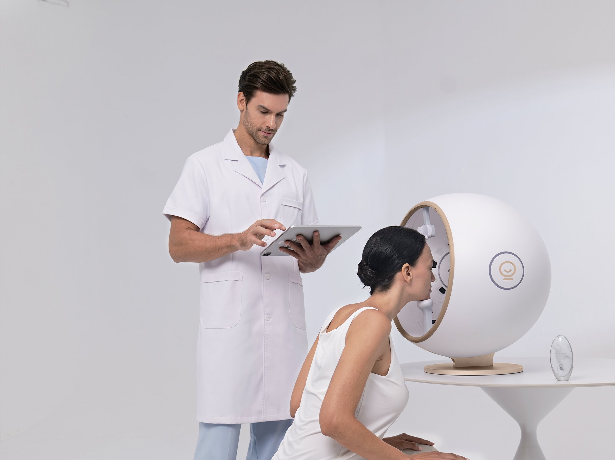 Aesthetician operating a skin and facial analysis device while a woman is seated with her head inside the machine, in a MedSpa setting.