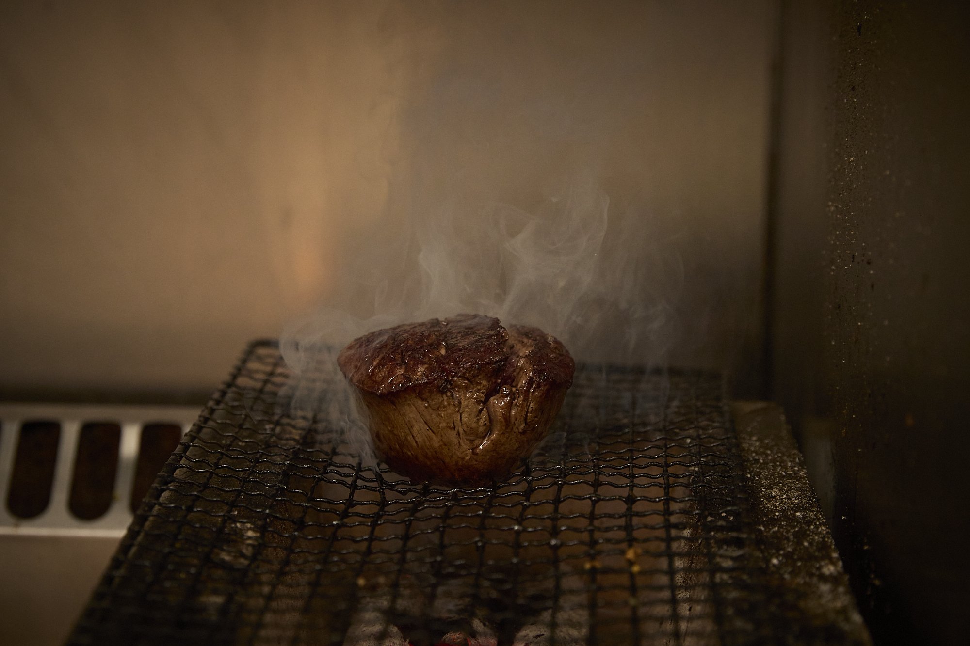A baked meatloaf is smoking on a wire rack inside an oven.