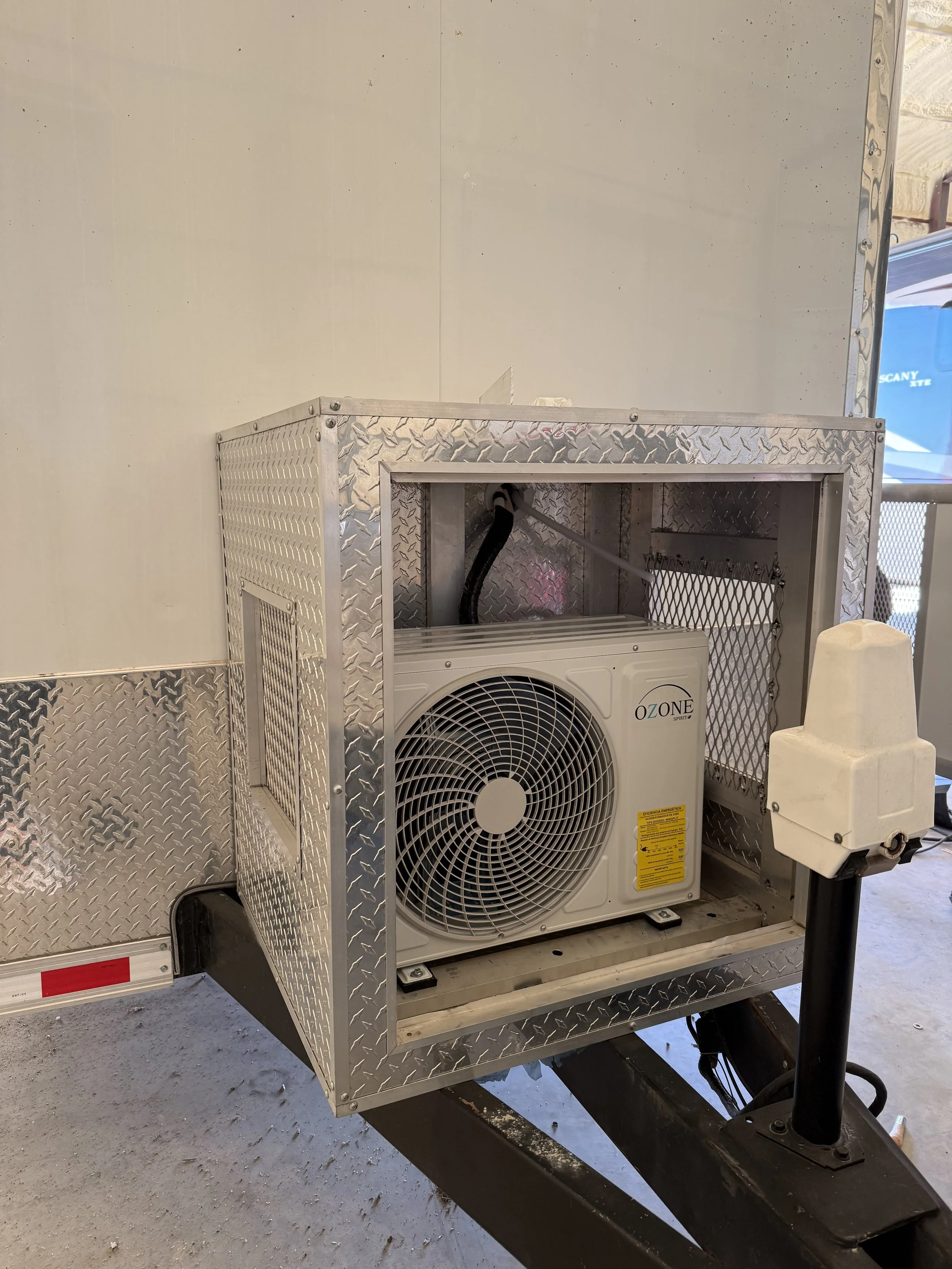A metal enclosure with diamond plate pattern, housing an air conditioning unit labeled 'Ozone'.