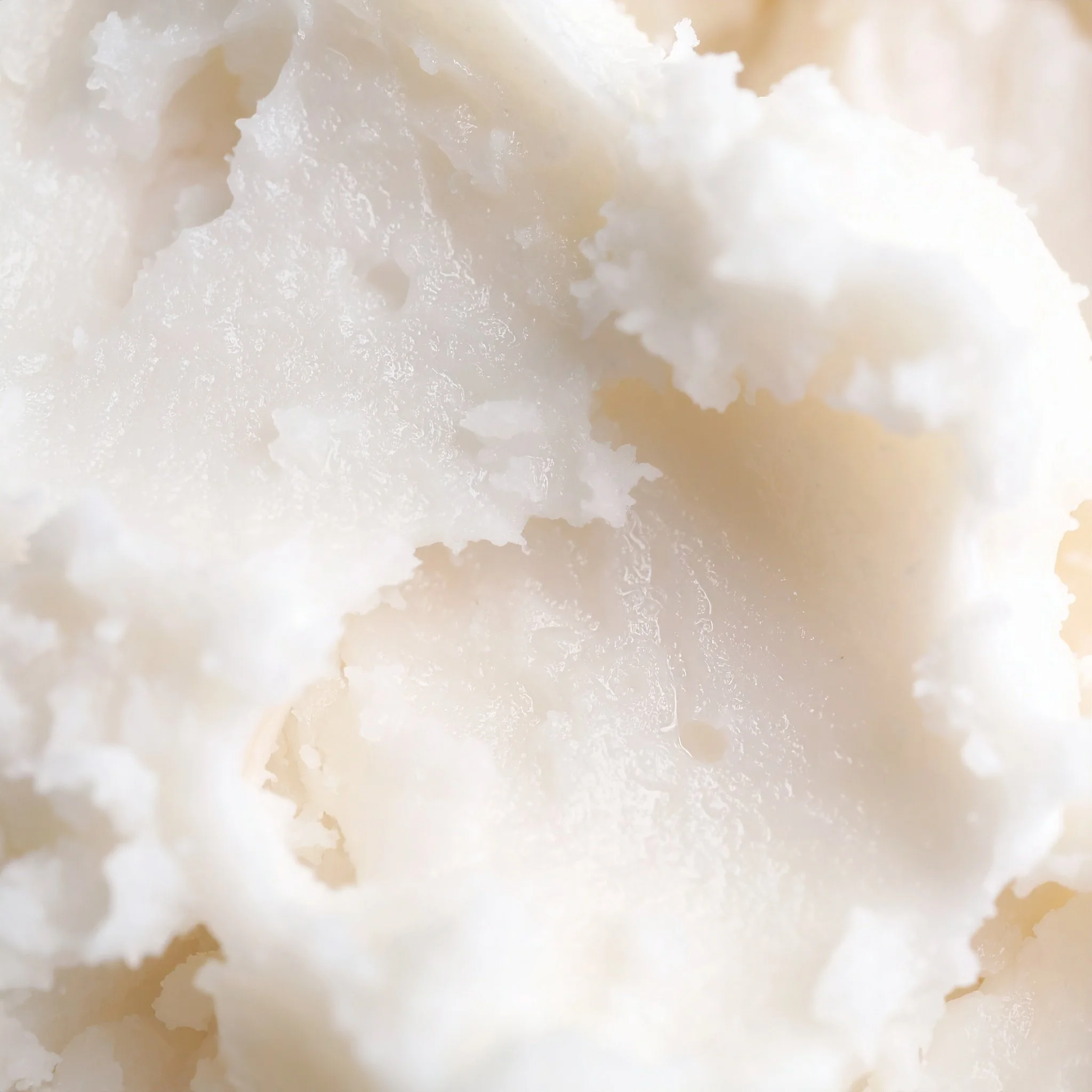 Close up image of creamy, white Shea Butter texture with wet shine