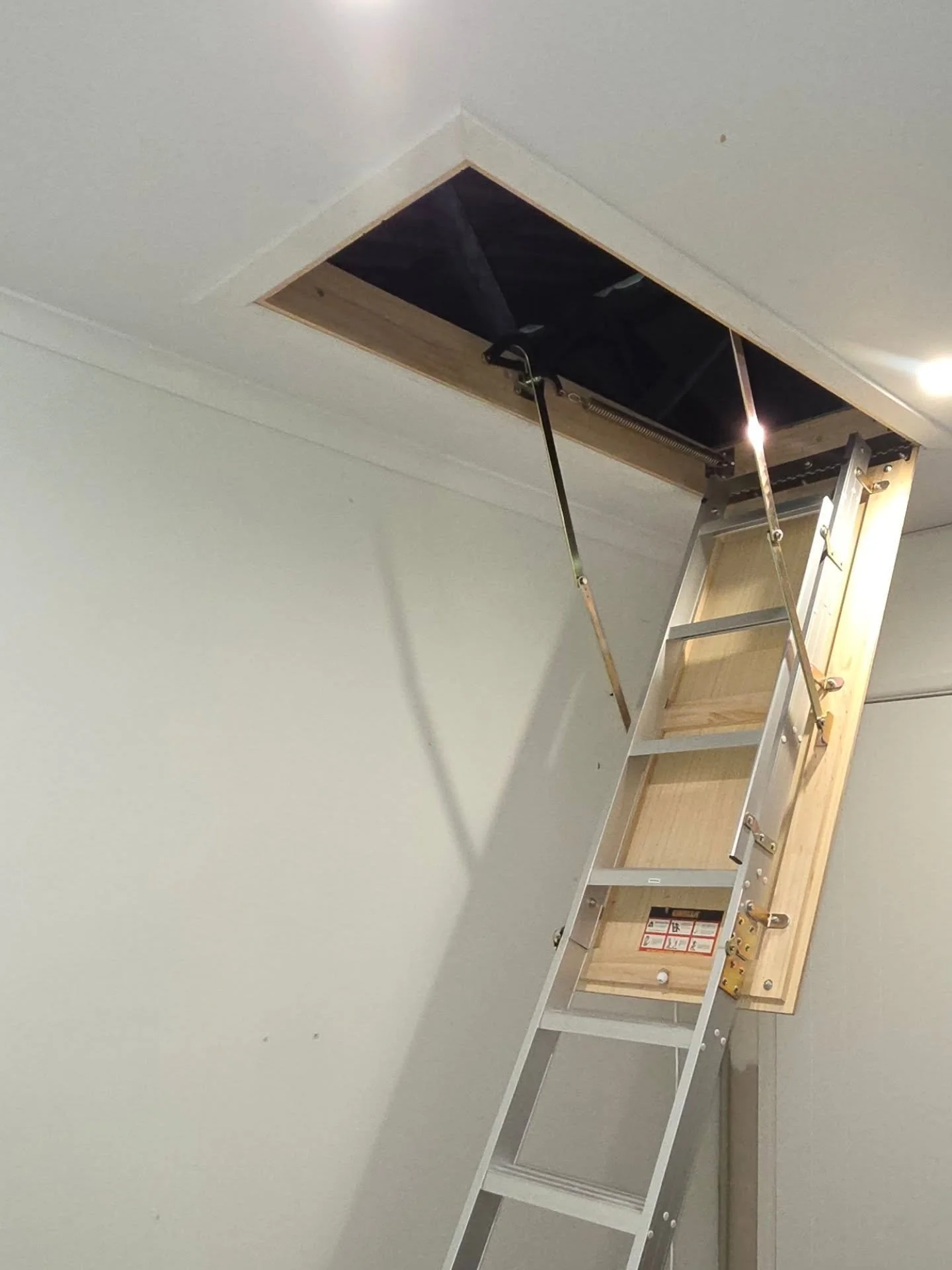 Turned a simple manhole in the spare bedroom into a full attic access with pull-down stairs.

We opened up the ceiling, installed attic stairs, and laid yellow tongue flooring in the roof space to create a solid storage area.

The ultimate storage ha