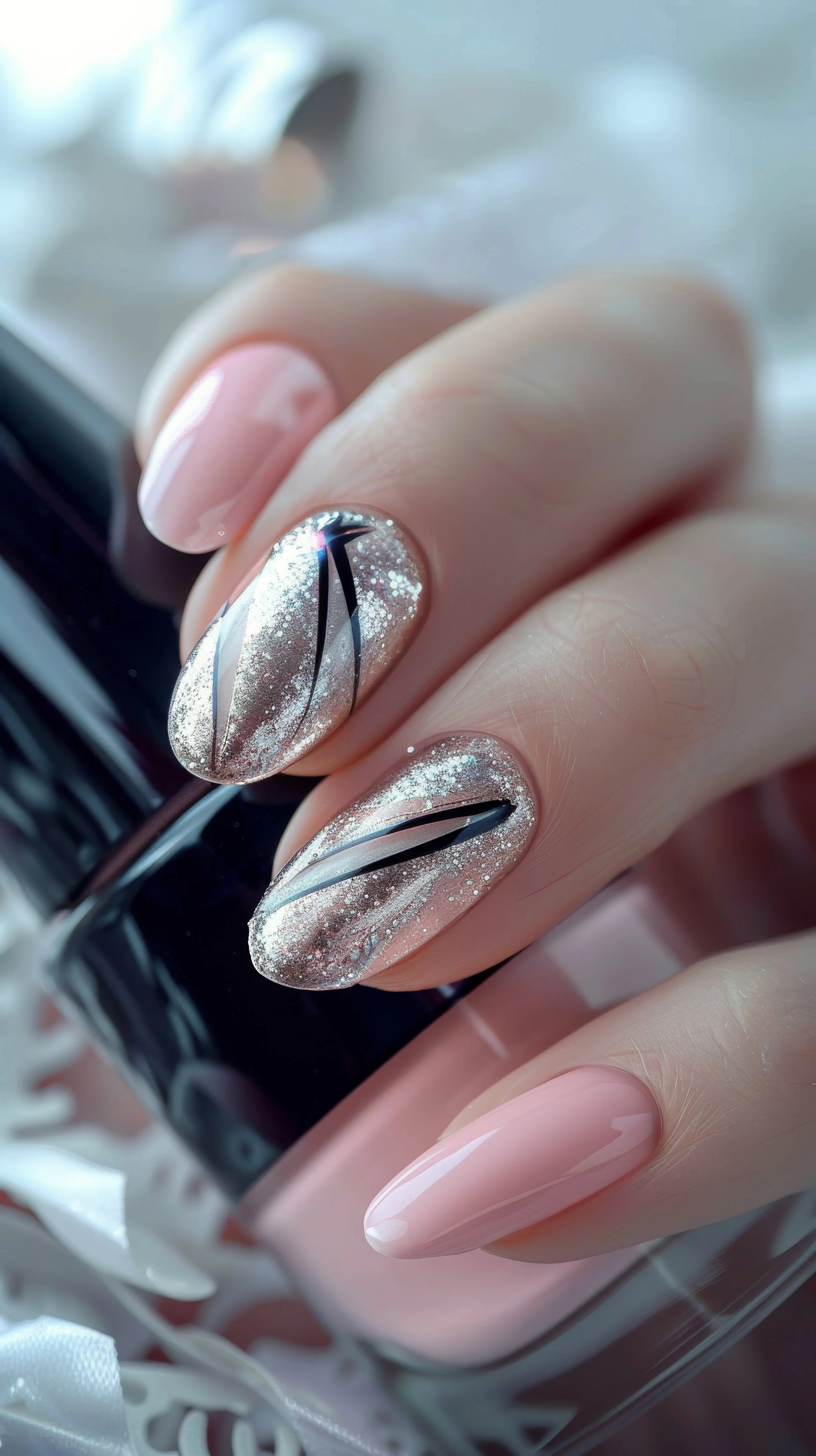 Close-up of a hand with decorated and glossy painted nails holding a nail polish bottle. The nails have a nude base with black, silver, and glitter accents, featuring a striped design.