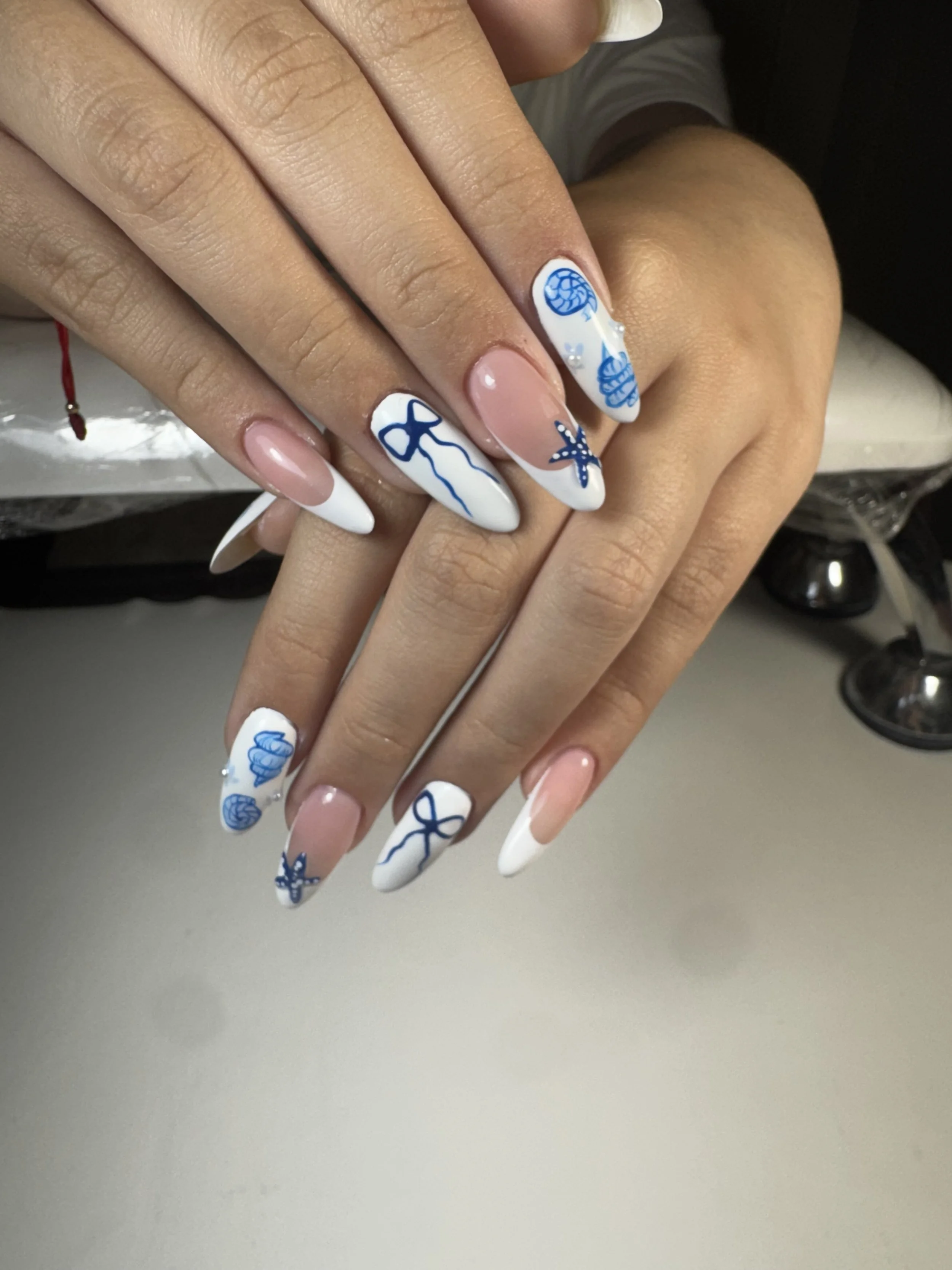 Nail art with blue sea creatures and shells on a French manicure base.