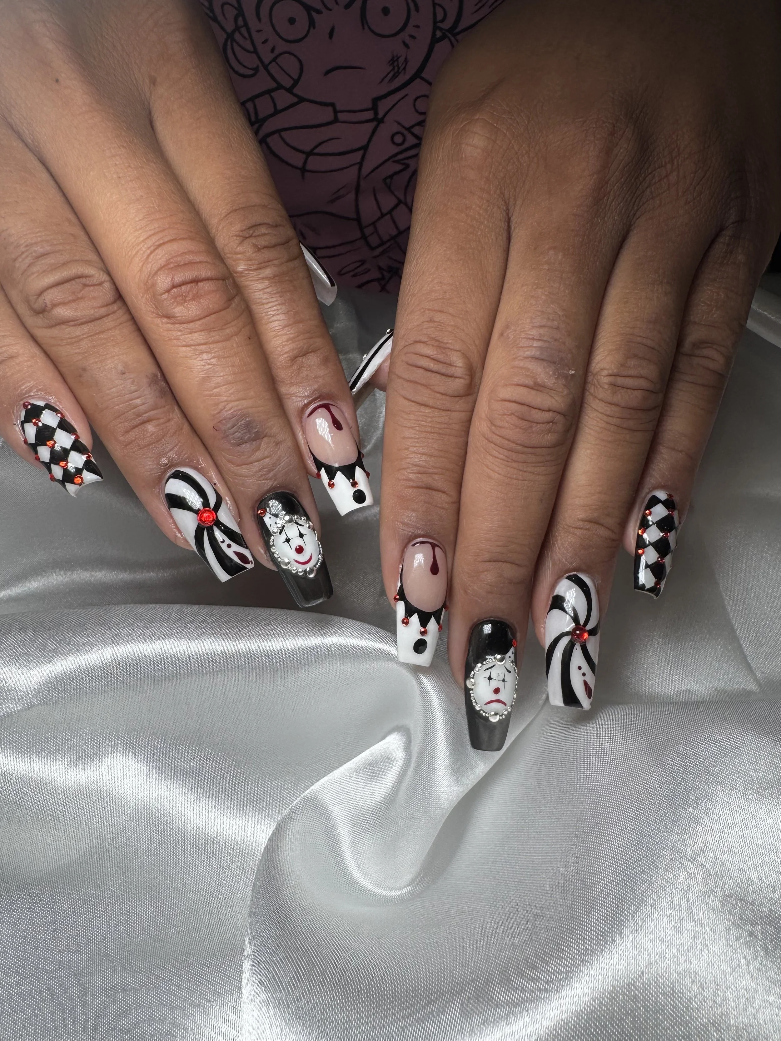 Nail art with black, white, red, and silver colors featuring candy cane, clown faces, and abstract patterns.