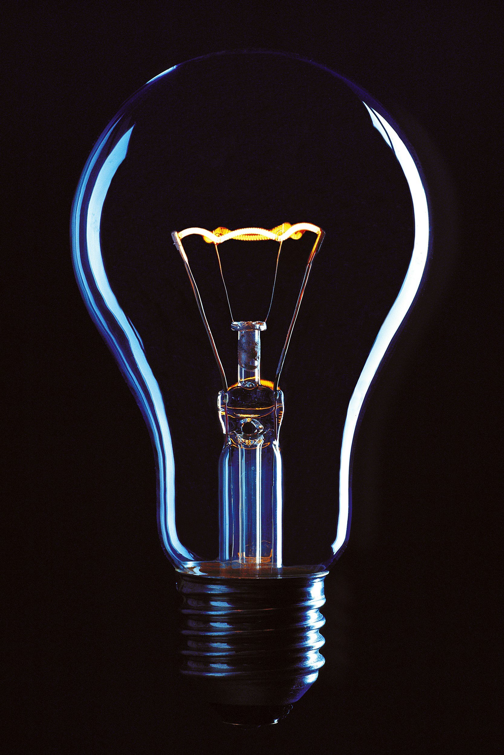 Close-up of a glowing incandescent light bulb against a dark background.