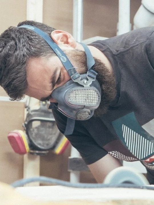 Founder, Samir, with safety goggles and a dust mask working on a project in a workshop setting.
