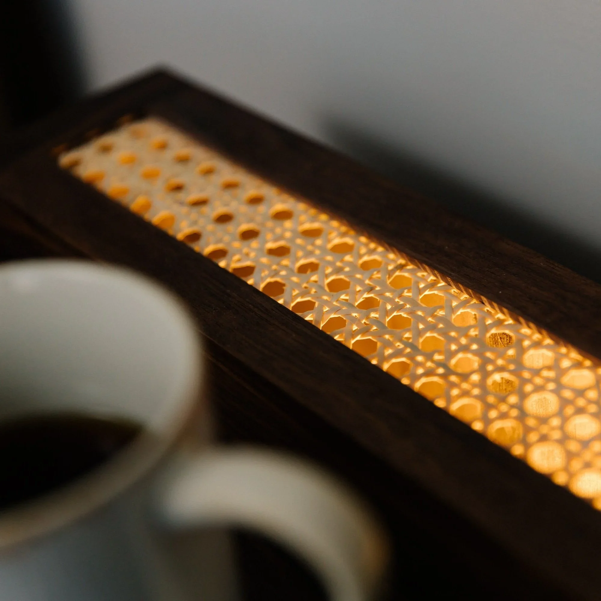 Close-up of a wooden-framed tea light holder with an intricate carved design, lit from inside, casting a warm glow.