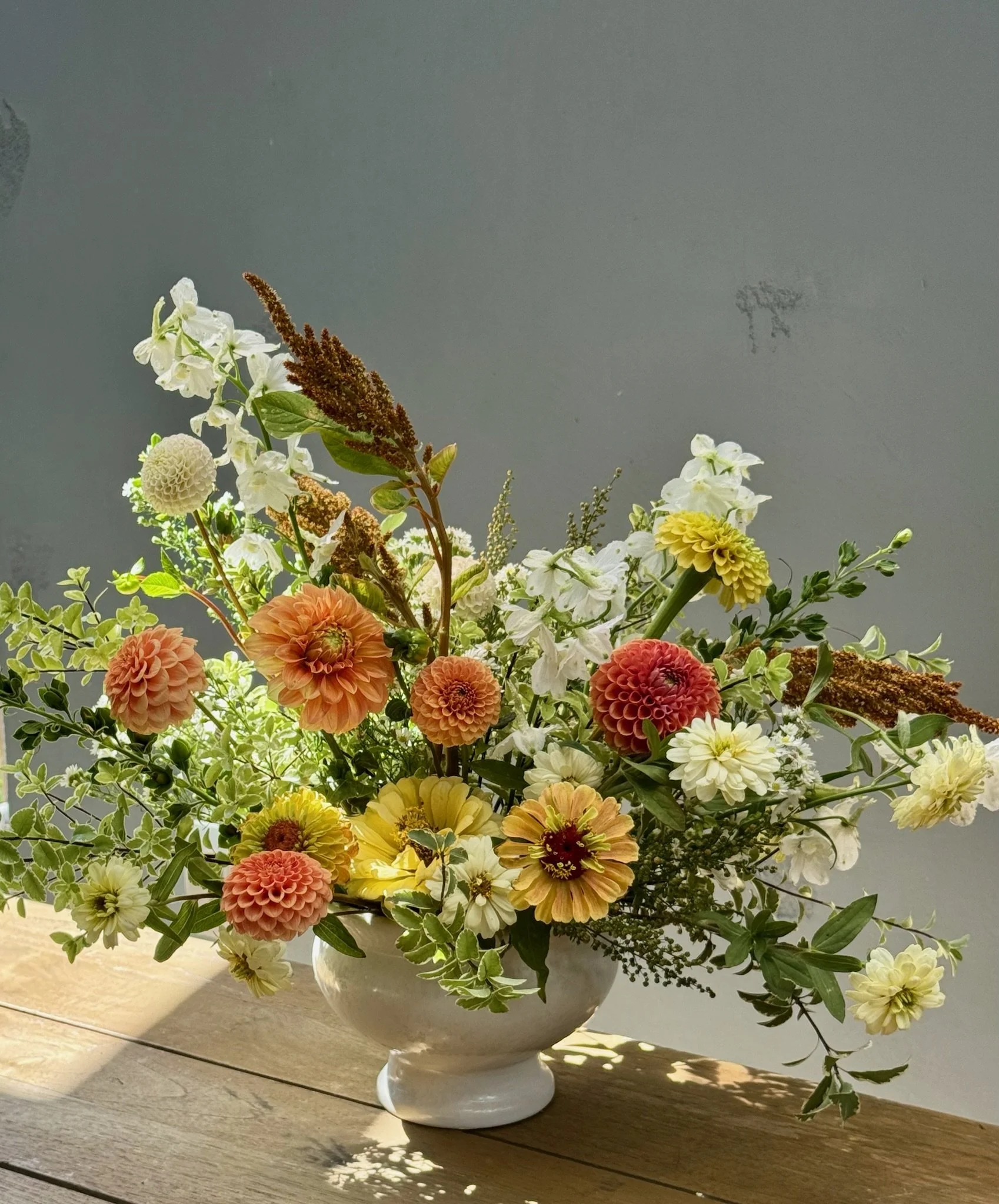 Arrangement of dahlias, zinnias, and seasonal wildflowers in peach, yellow, and white.