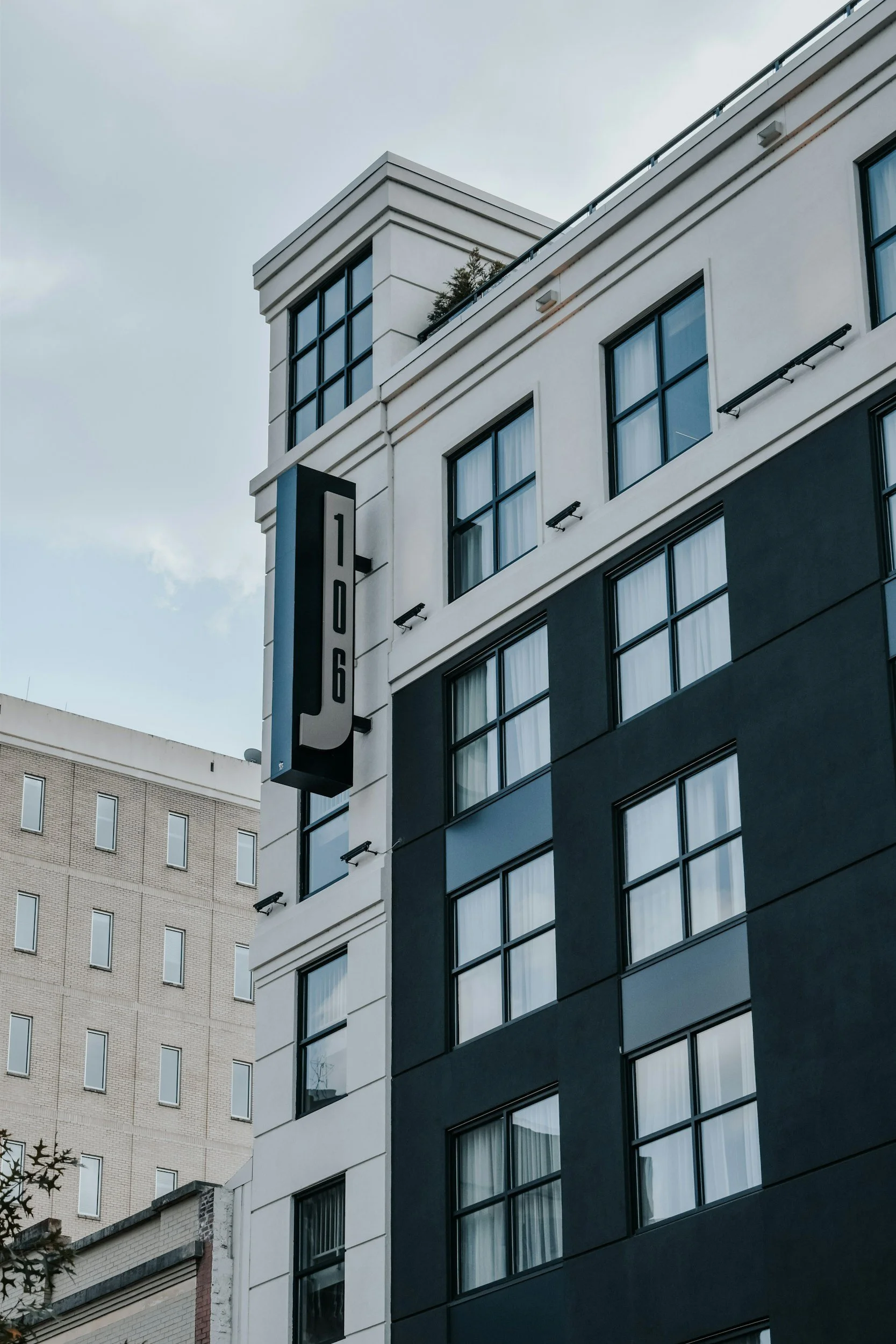 Modern multi-story building with large windows and a vertical sign reading '106' on a blue background.