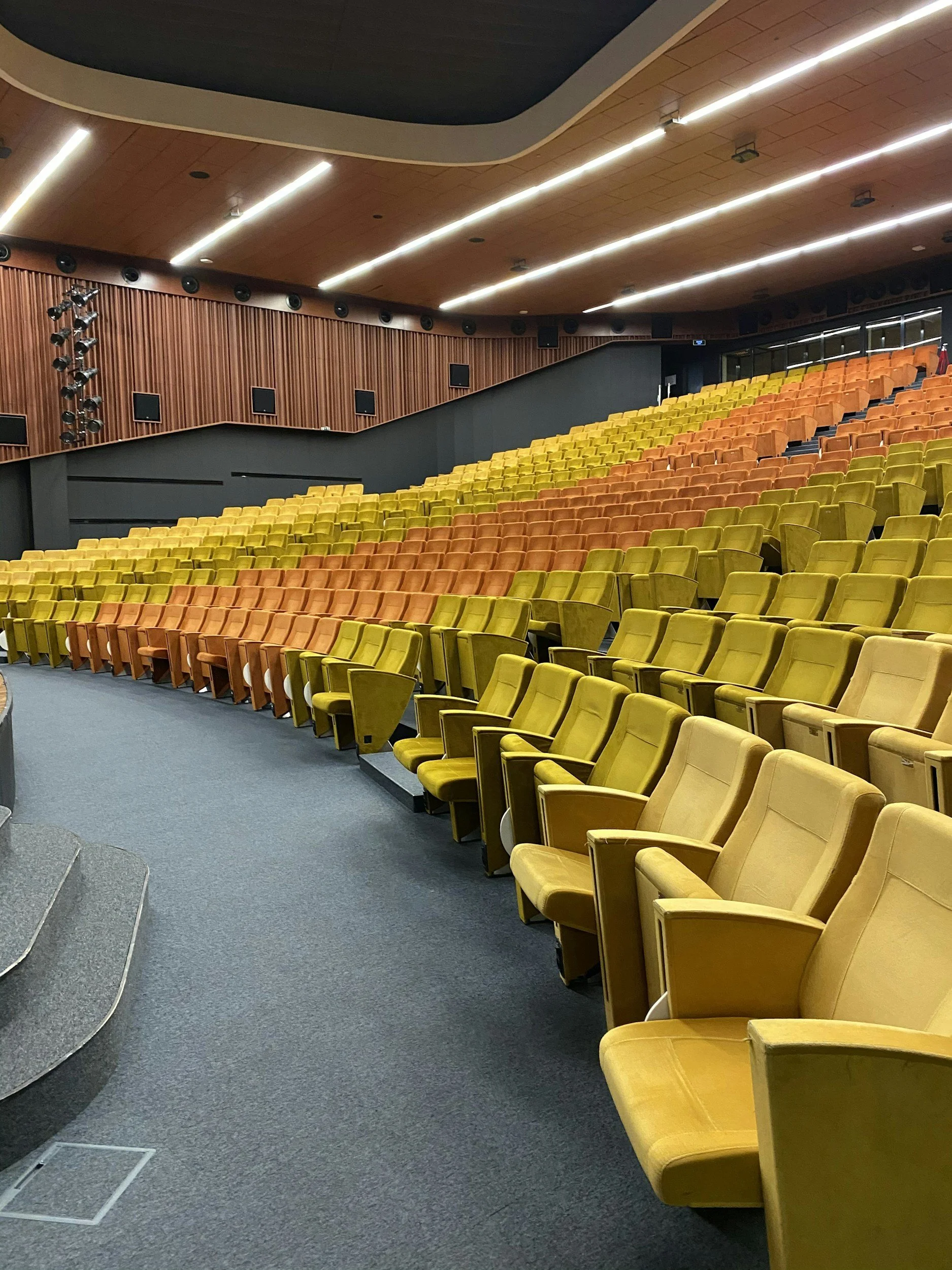 Interior of a theater or auditorium with yellow and orange seats arranged in tiers.