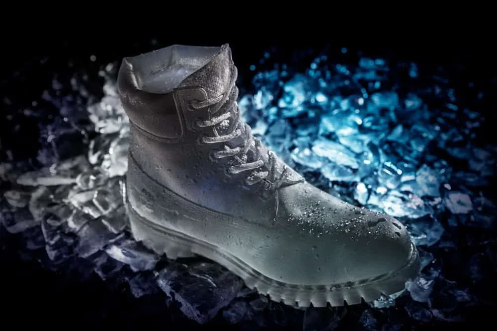 An ice sculpture of a Timberland 6" boot illuminated with white and blue lights on a bed of crushed ice.