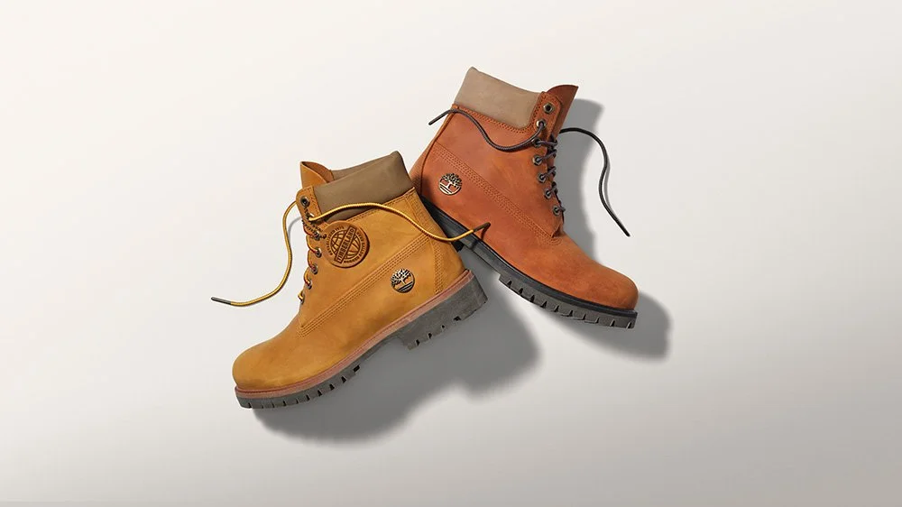 Two pairs of Timberland-style work boots, one yellow and one brown, placed on a white surface.
