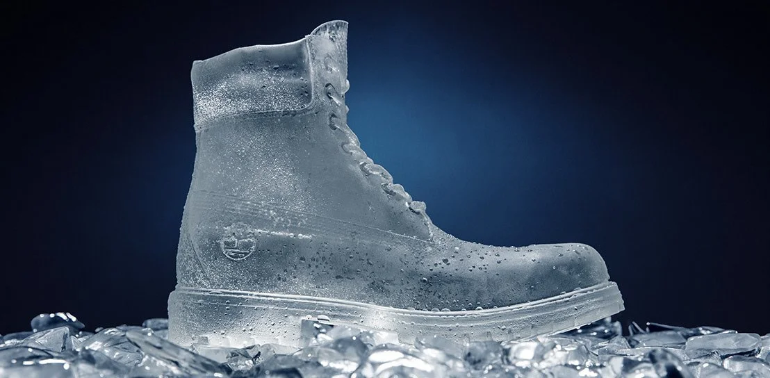 A transparent ice sculpture of Timberland 6" boot, sitting on crushed ice with a dark background.